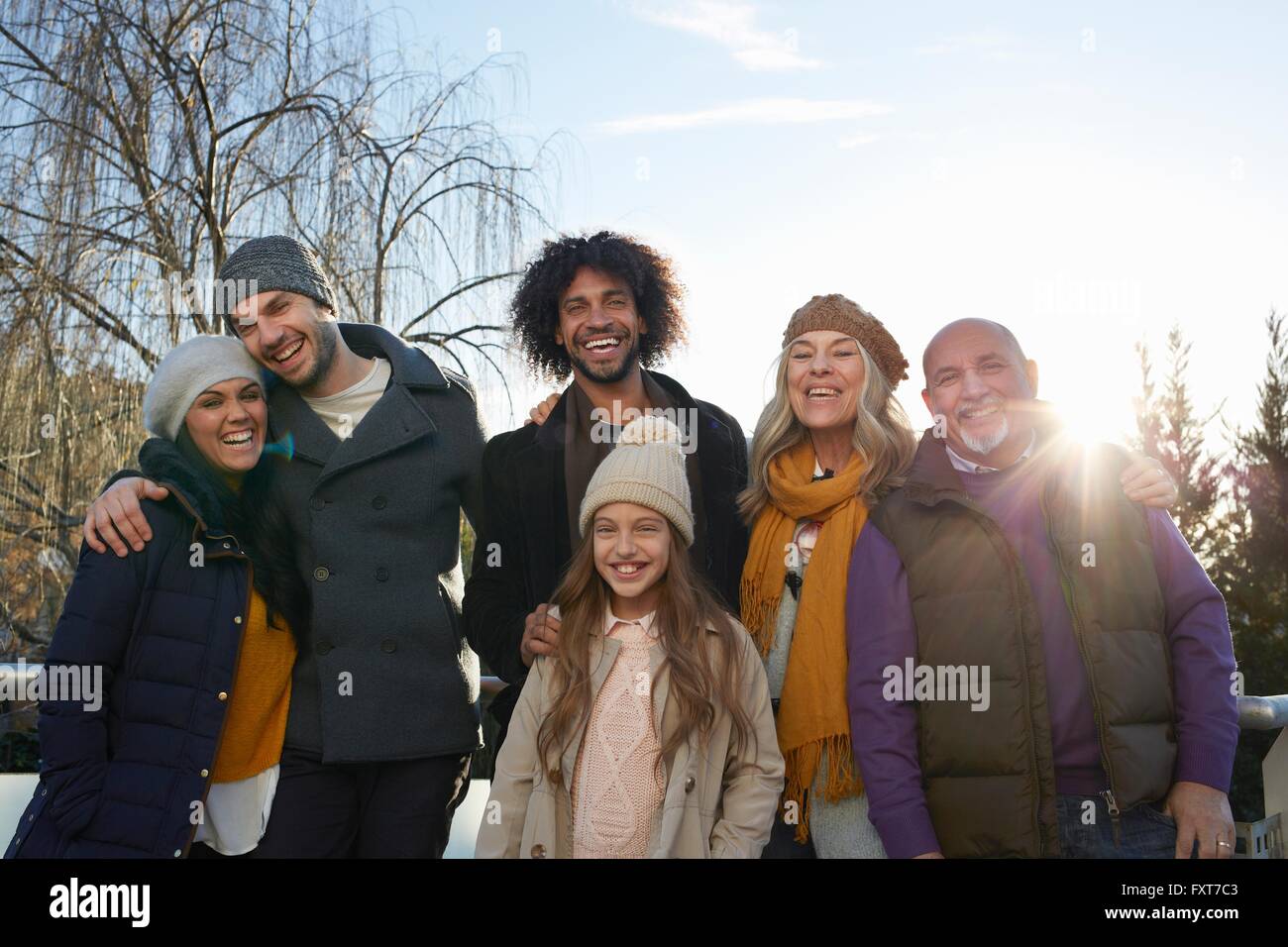 Multi familia generacional abrigos y tejer sombreros mirando sonriente familia Foto de stock