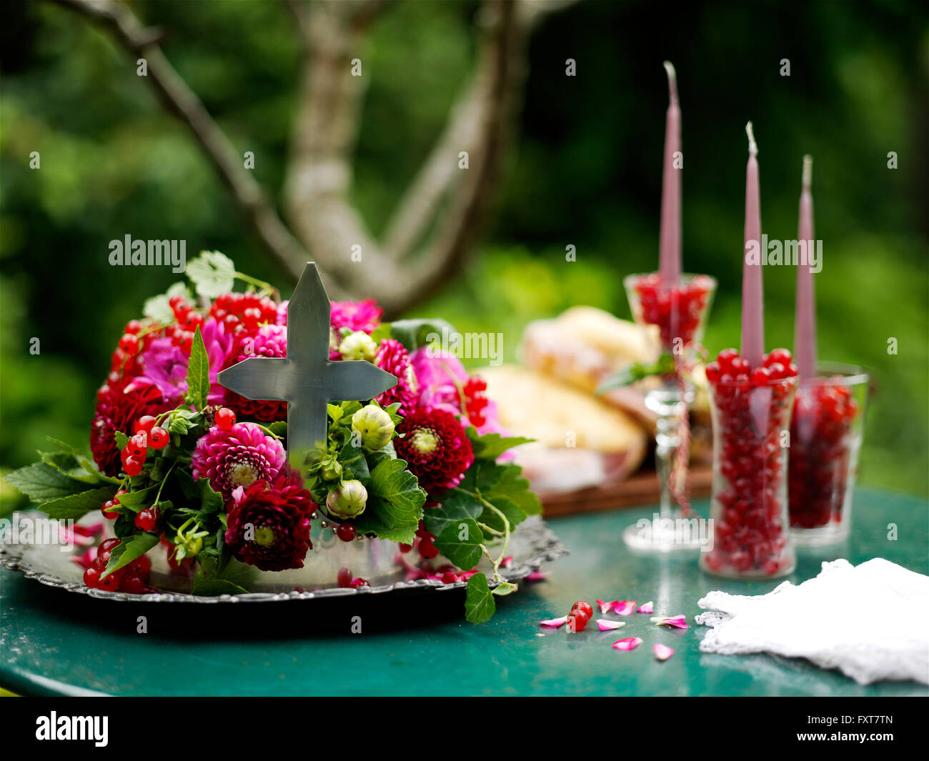 Arreglo floral con gafas de redcurrants y velas sobre la mesa de