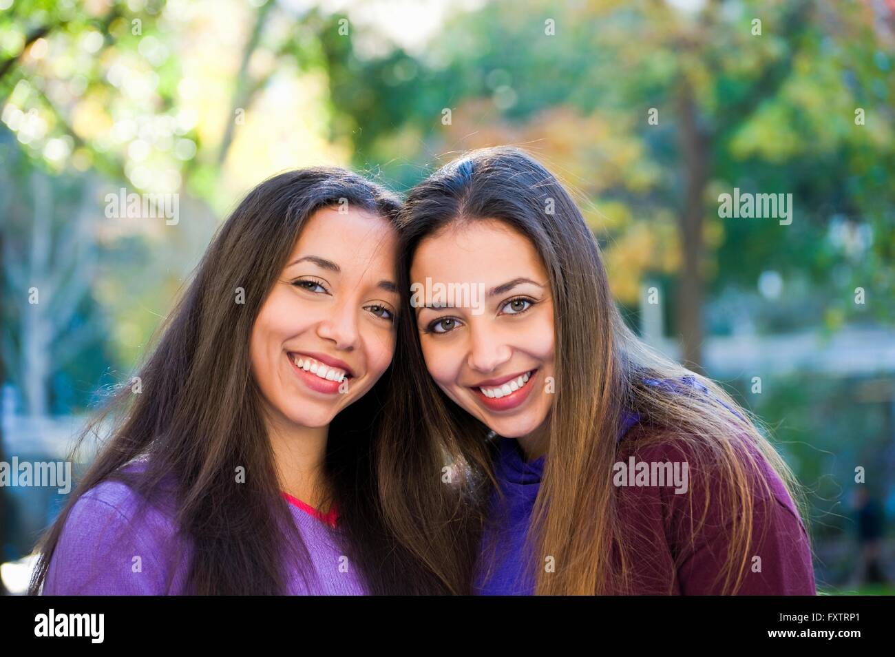 Hermanas gemelas sonriendo en estacionamiento Foto de stock