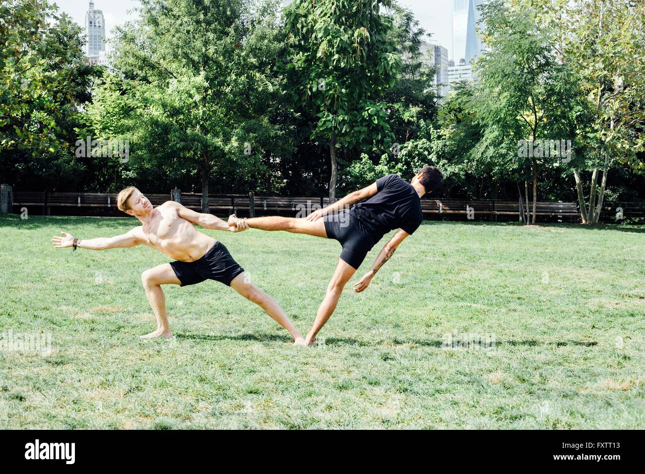 Dos hombres se inclina lateralmente en el yoga de pie en posición de espera park Foto de stock
