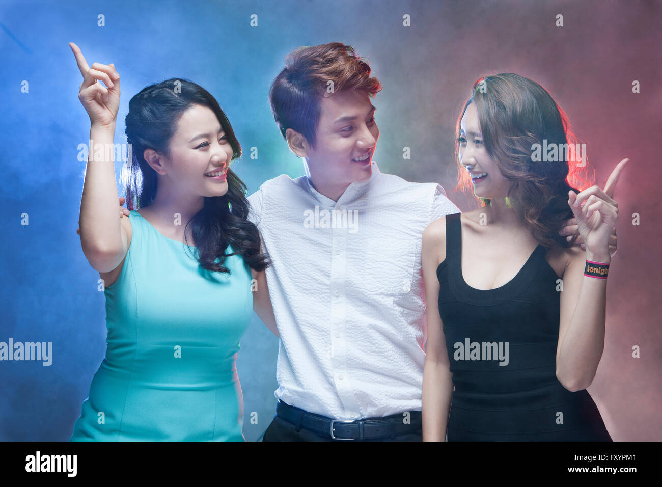 Retrato de tres jóvenes sonriente cara a cara en discoteca Foto de stock