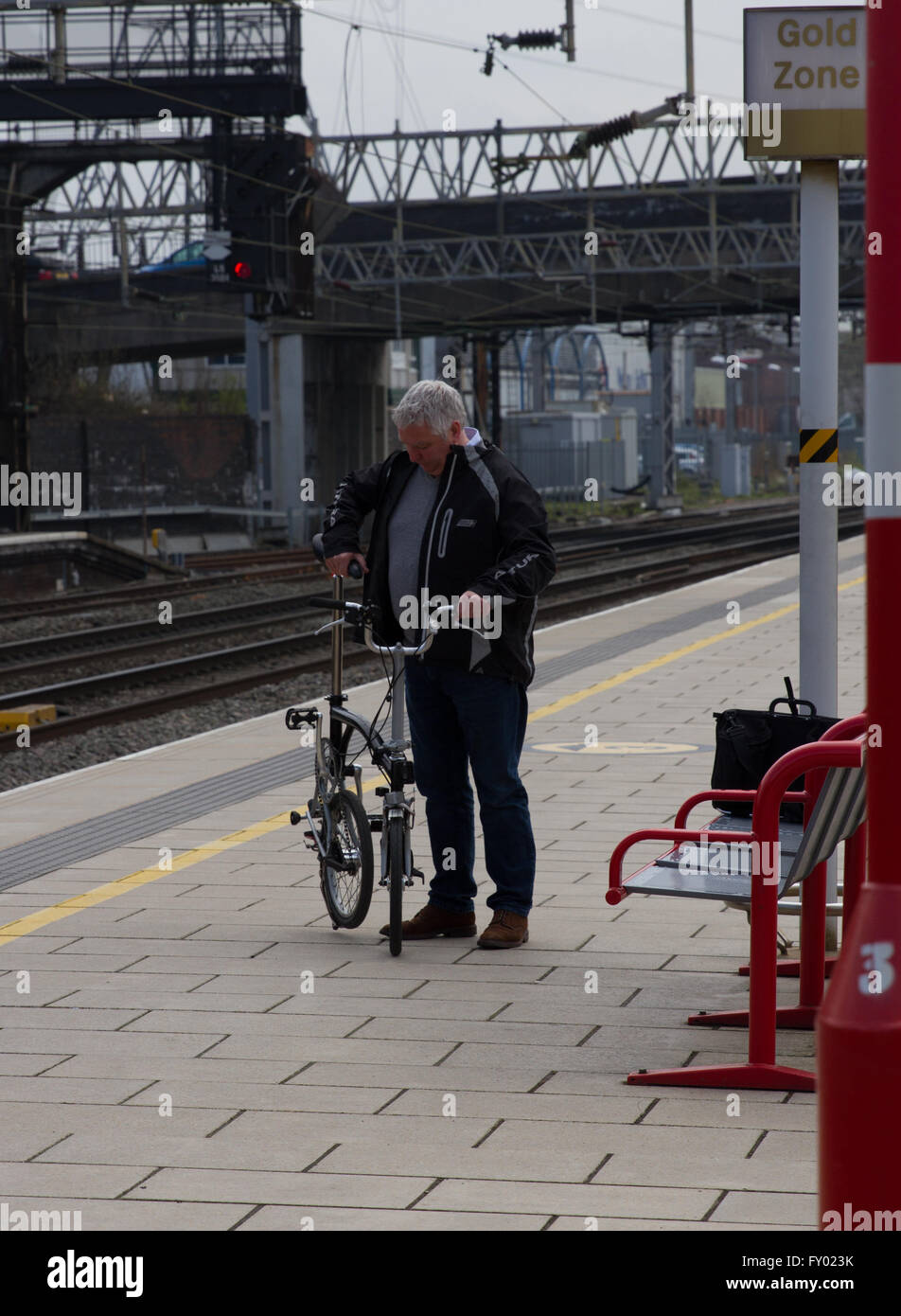 Un ciclista y espera a sus pasajeros de tren tren con una bicicleta plegable listo para cargar. Foto de stock