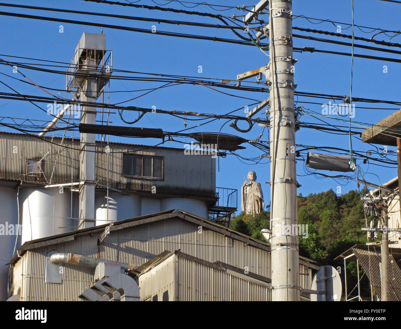 Buddah en la colina a través de los tendidos eléctricos industriales Matsuyama Japón Foto de stock
