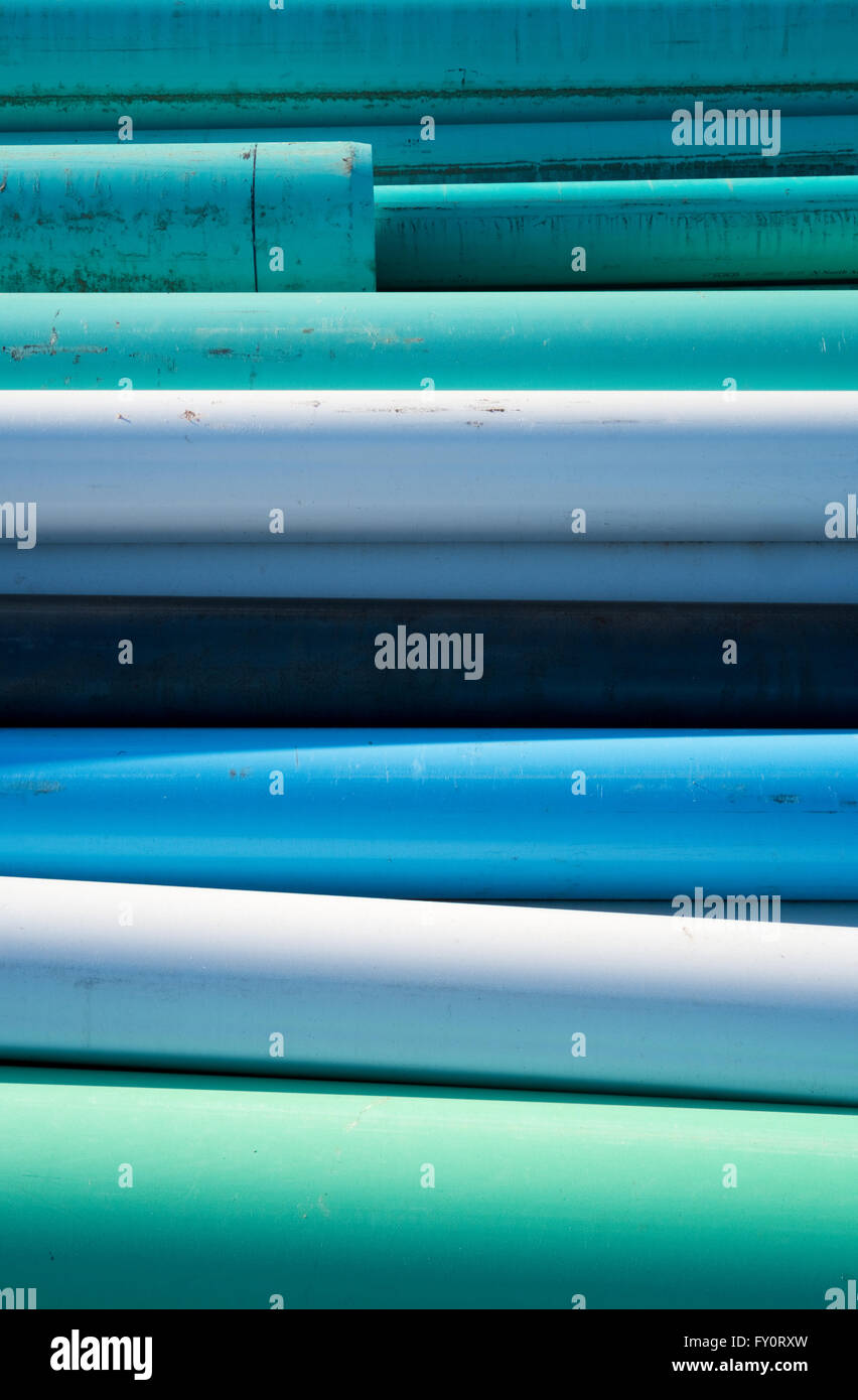 Resumen de azul, blanco y verde agua tubos apilados en un sitio de construcción en un día soleado Foto de stock