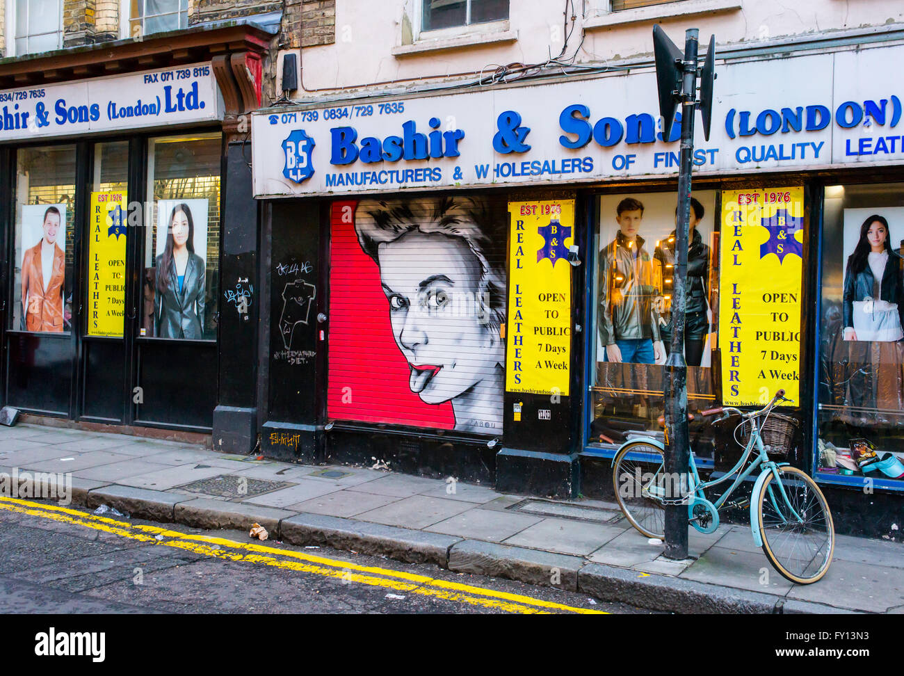 Ventana frontal de una tienda de ropa local con un fresco de graffiti que muestra una mujer con lengua colgante. Foto de stock