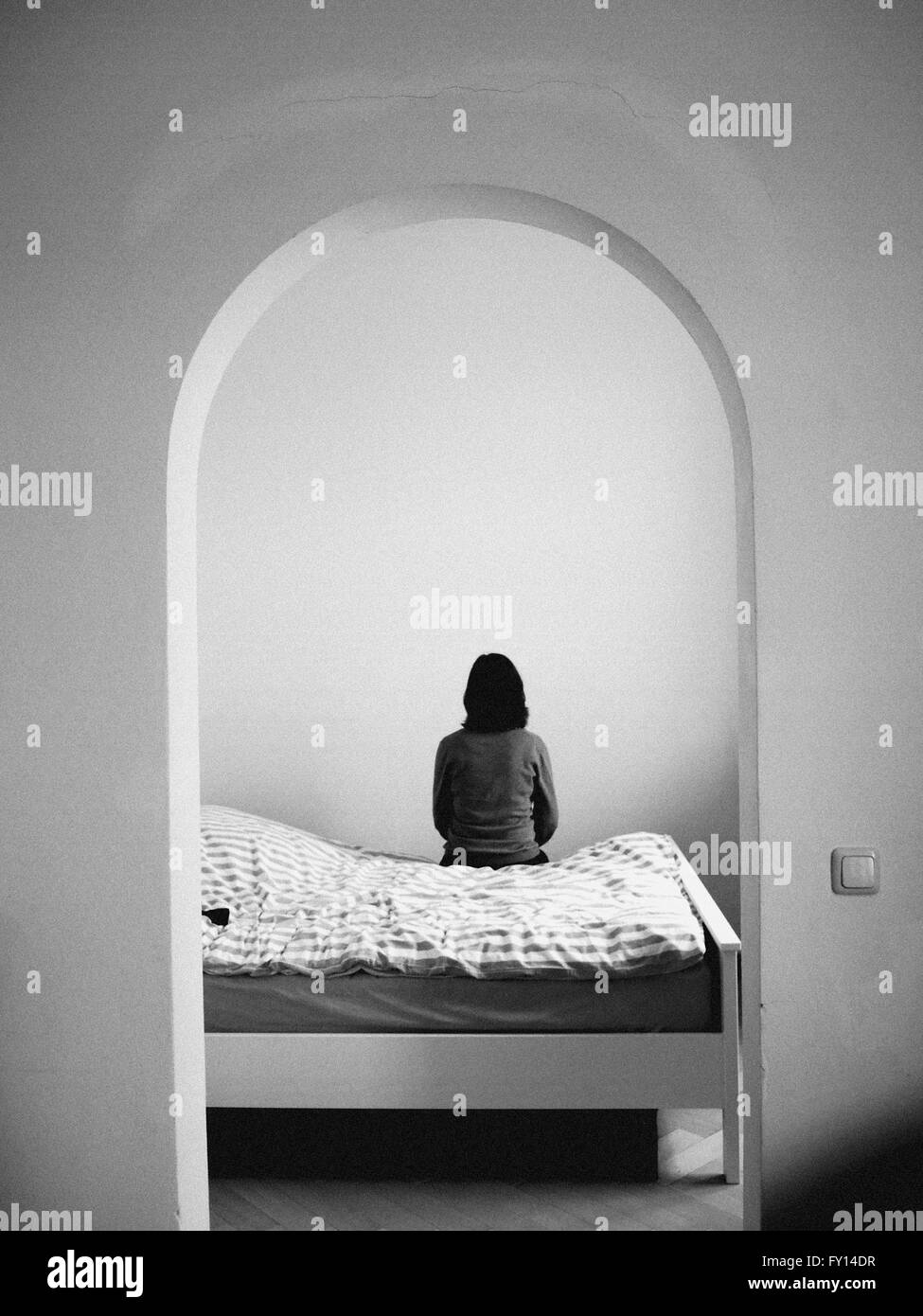 Vista trasera de una mujer sentada sobre una cama Foto de stock