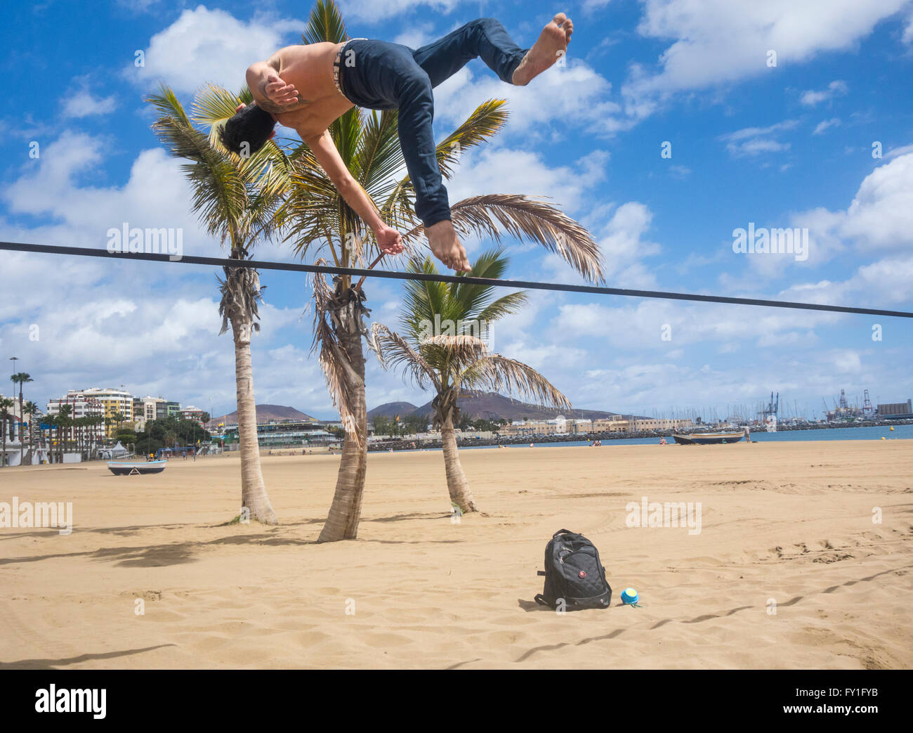 El hombre realizar volteretas y gimnasia desmonta en slackline atadas entre árboles de Plam Beach en España Foto de stock