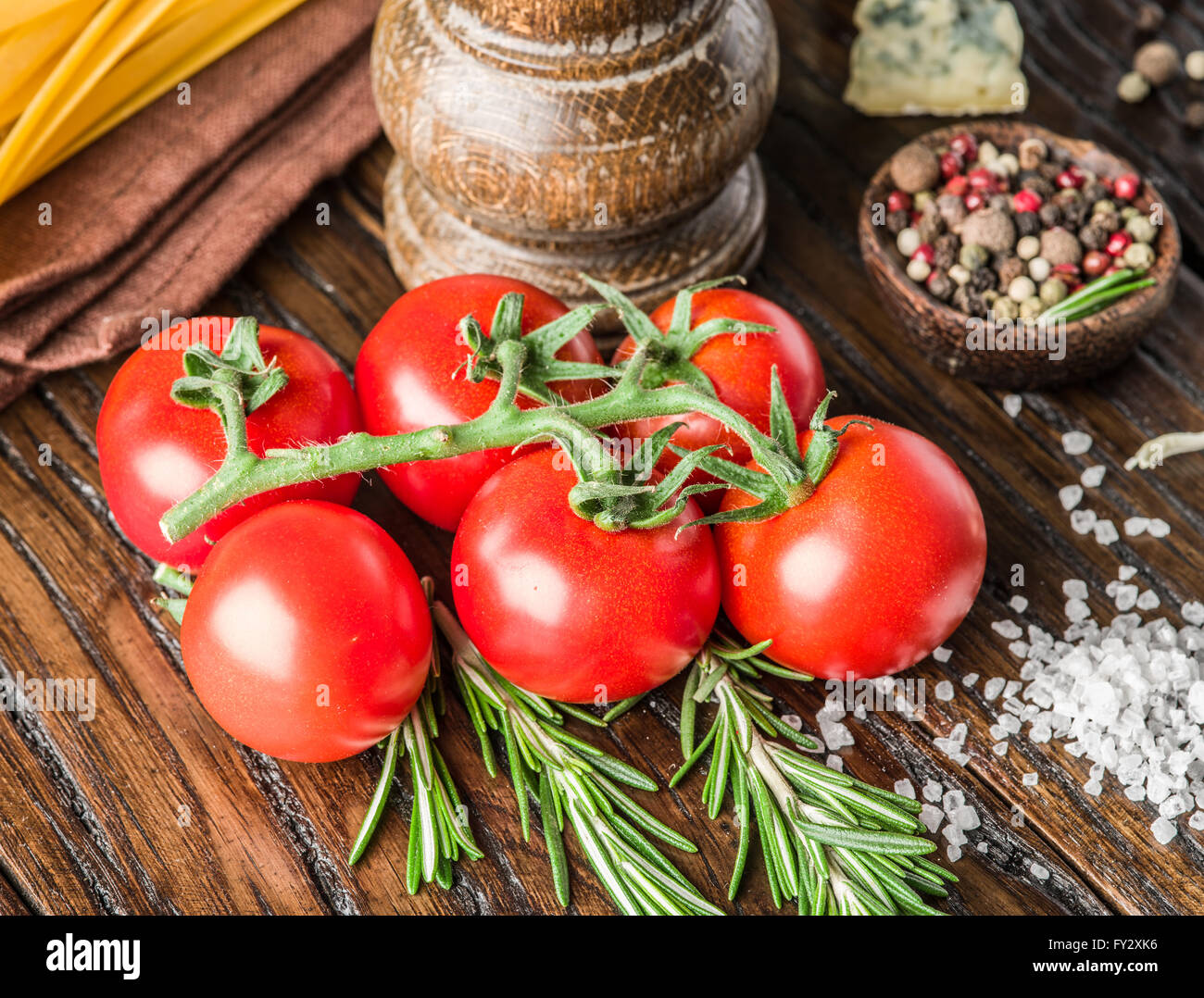 Pasta ingredientes. Tomates Cherry, spaghetti pasta, romero y especias sobre la mesa de madera. Foto de stock