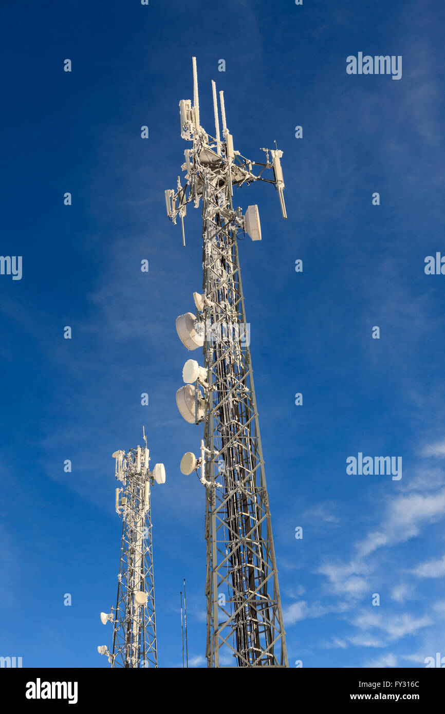 Comunicación de la torre de la antena, el transmisor y el cielo azul brillante en invierno Foto de stock