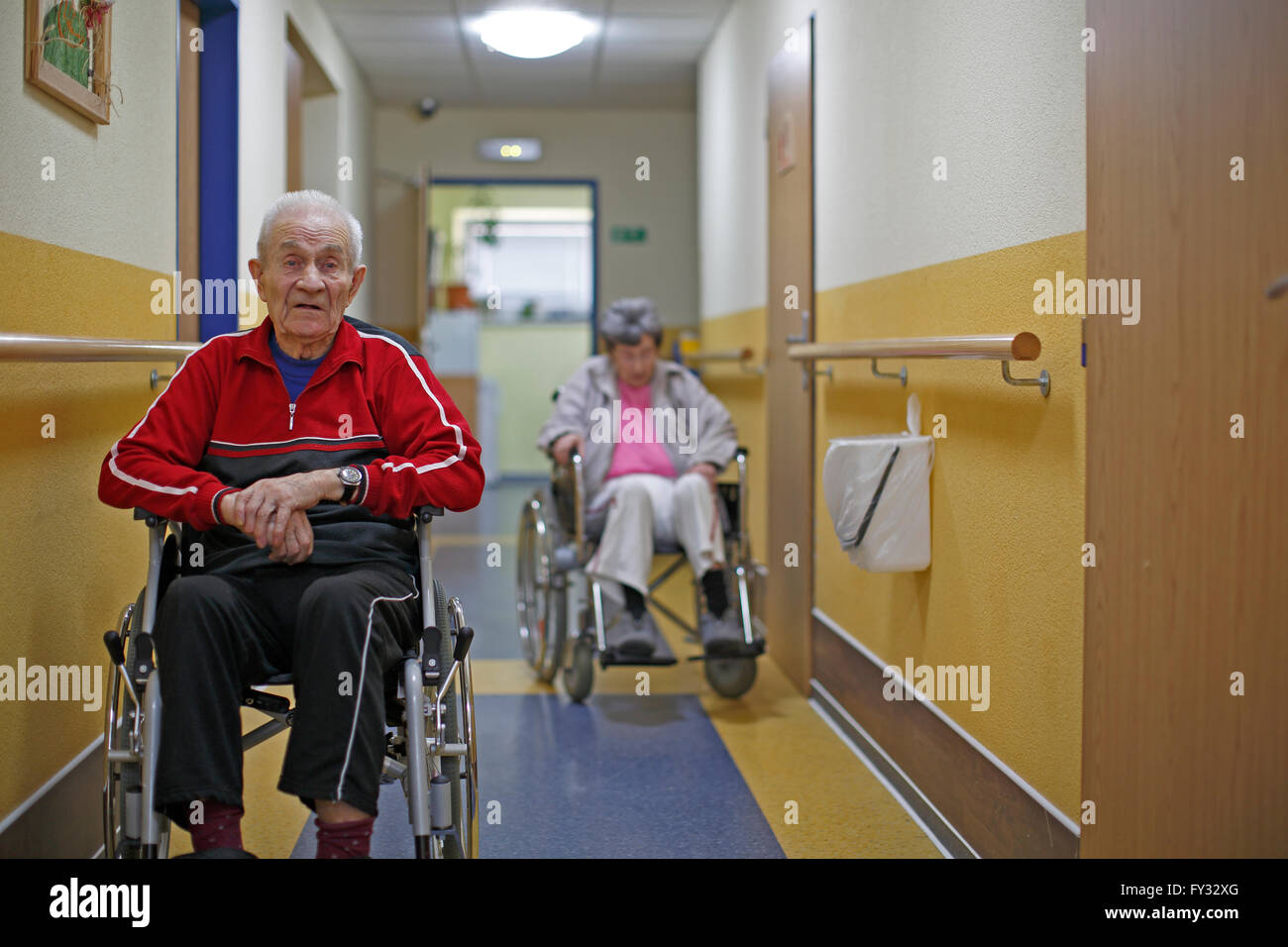 Dos ciudadanos de la tercera edad en sillas de ruedas, un hombre de 87 años y una mujer de 81 años, hogar de ancianos Foto de stock