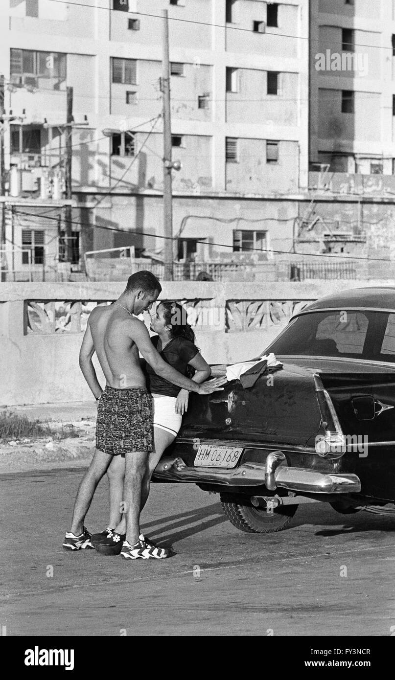 Pareja joven descansando sobre Chevrolet, La Habana, Cuba Foto de stock