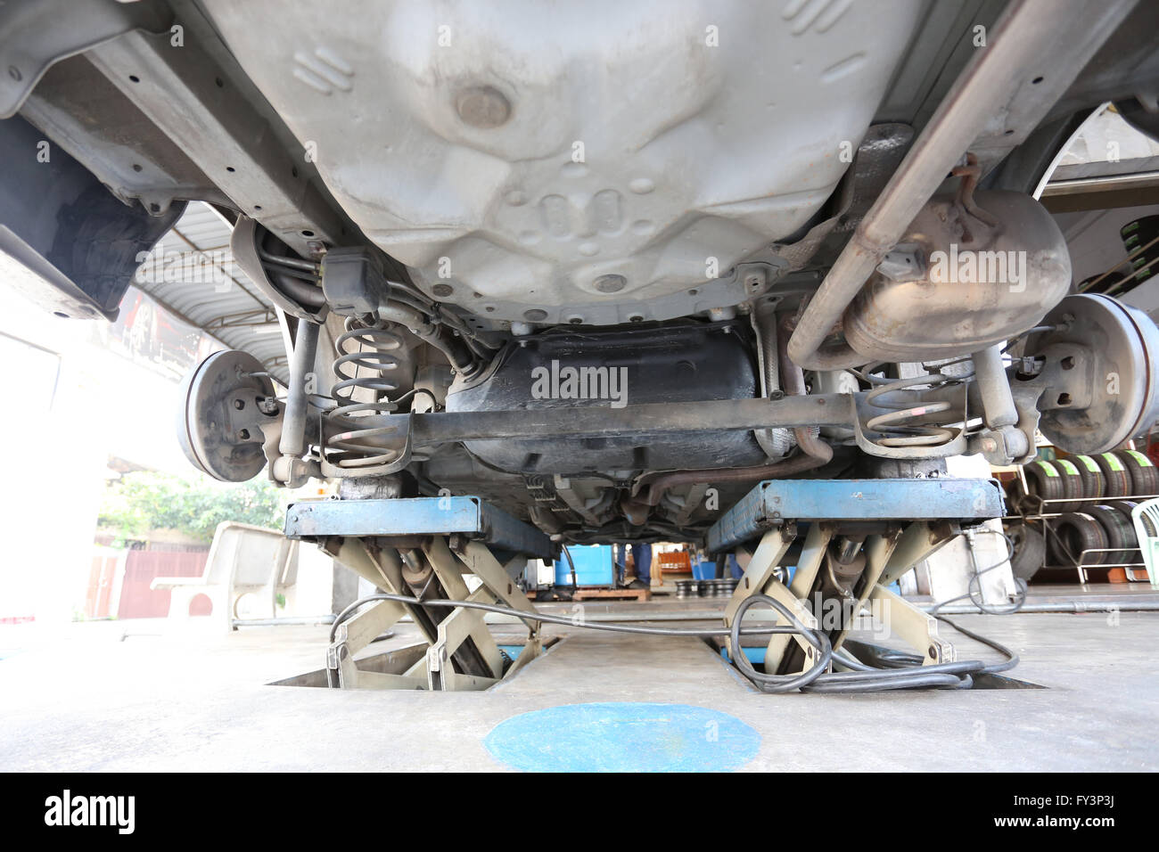 Mirar debajo del coche en el momento de la inspección de mantenimiento en la tienda del garaje. Foto de stock