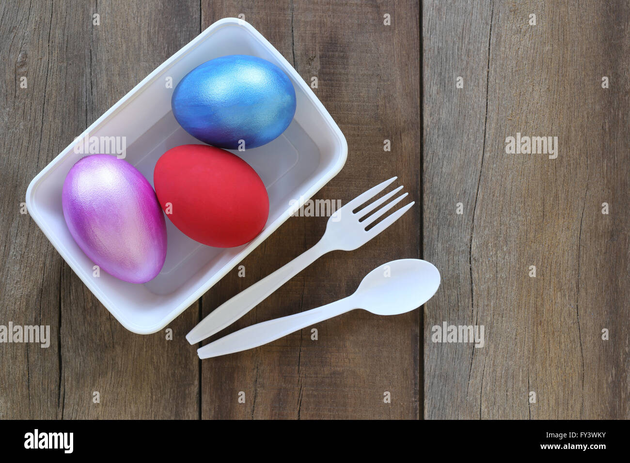 Huevo de pascua una variedad de colores en el recipiente de plástico y una cuchara, tenedor sobre fondo de madera vieja. Foto de stock
