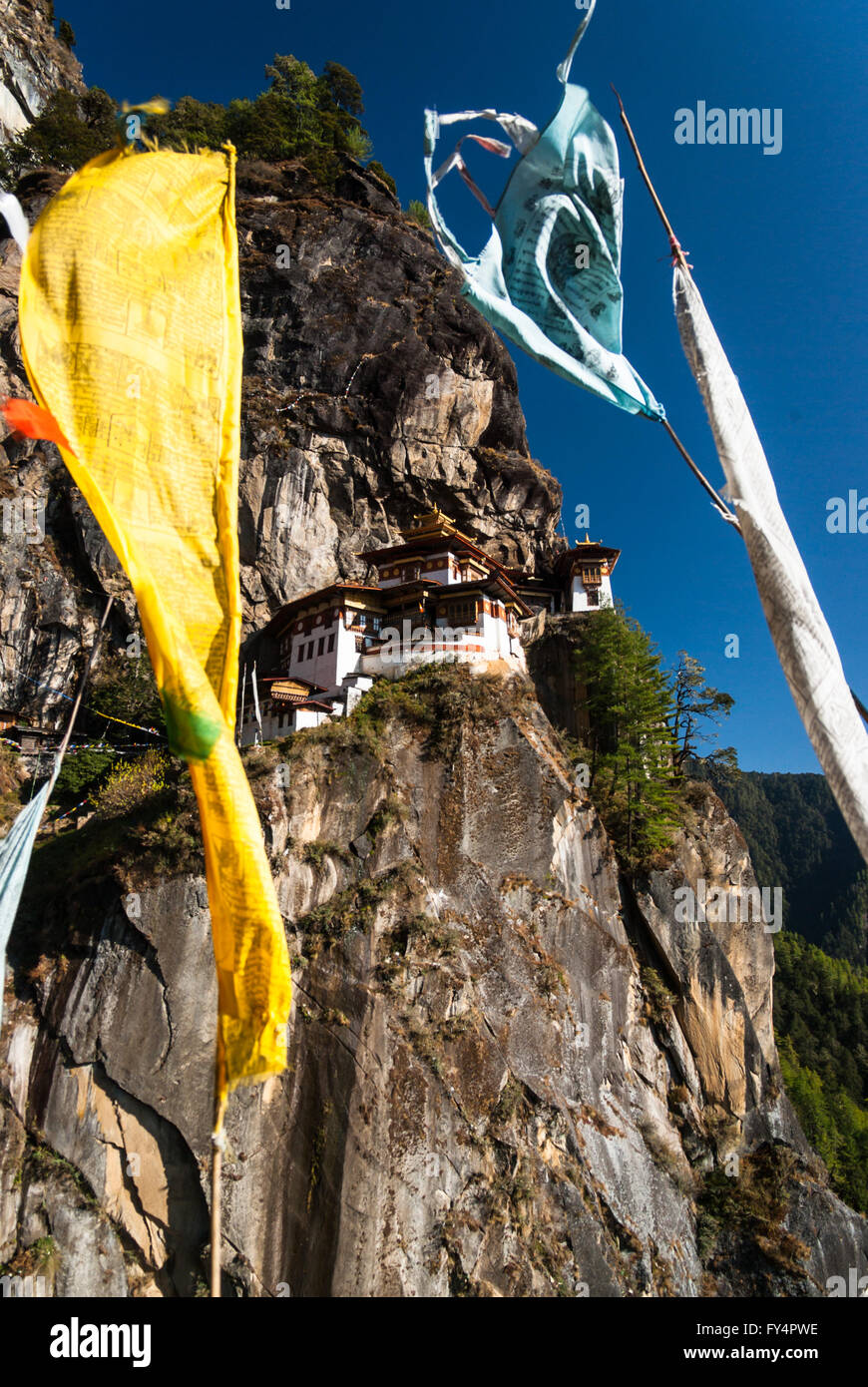 Ver a través de la oración banderas a Tiger's Nest (Monasterio de Taktshang), encaramado sobre un acantilado cerca de Paro, Bhután Foto de stock