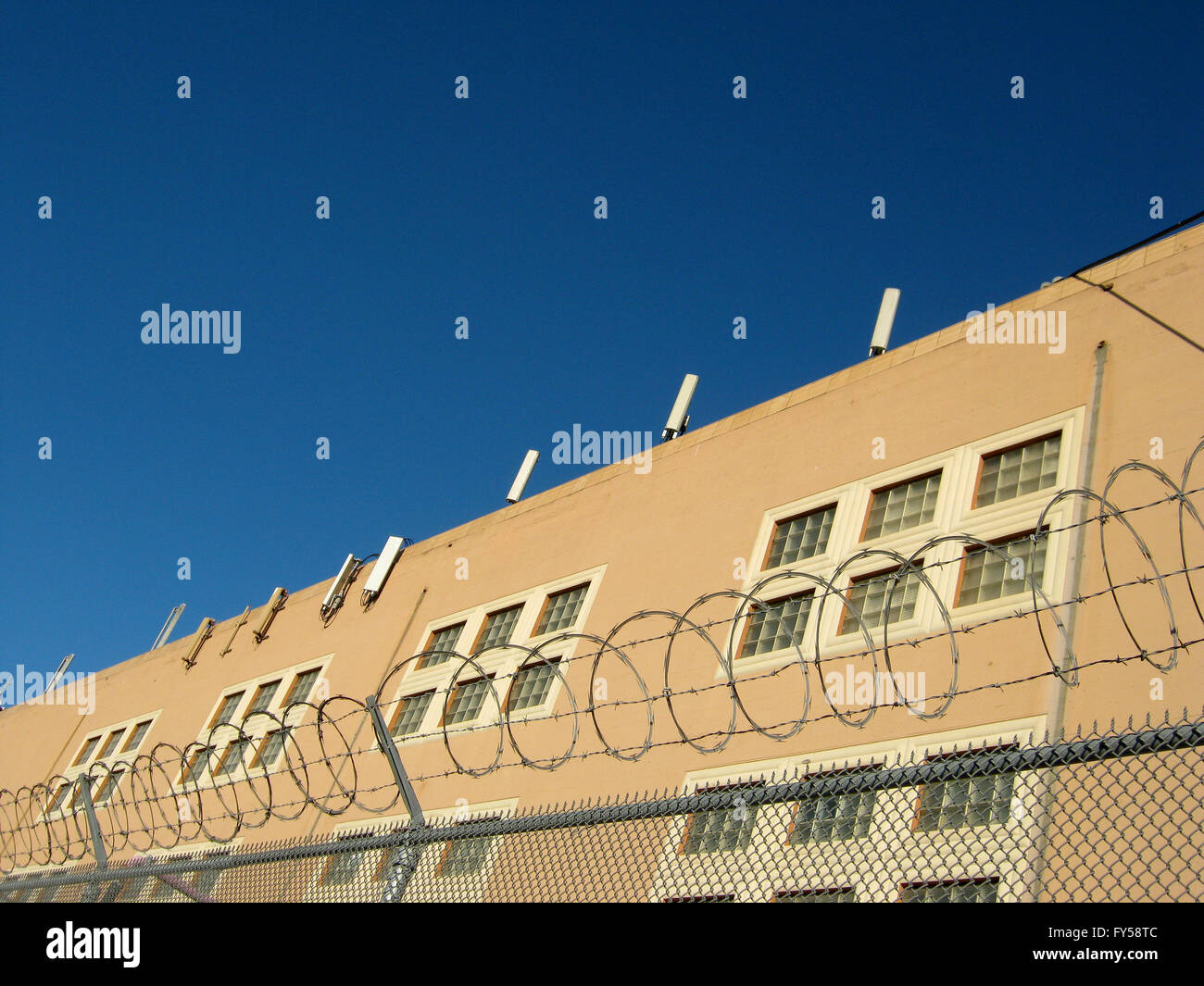 Torres celulares línea en la parte superior del edificio en San Francisco, California, con un cielo azul y detrás de barbwire valla. Foto de stock