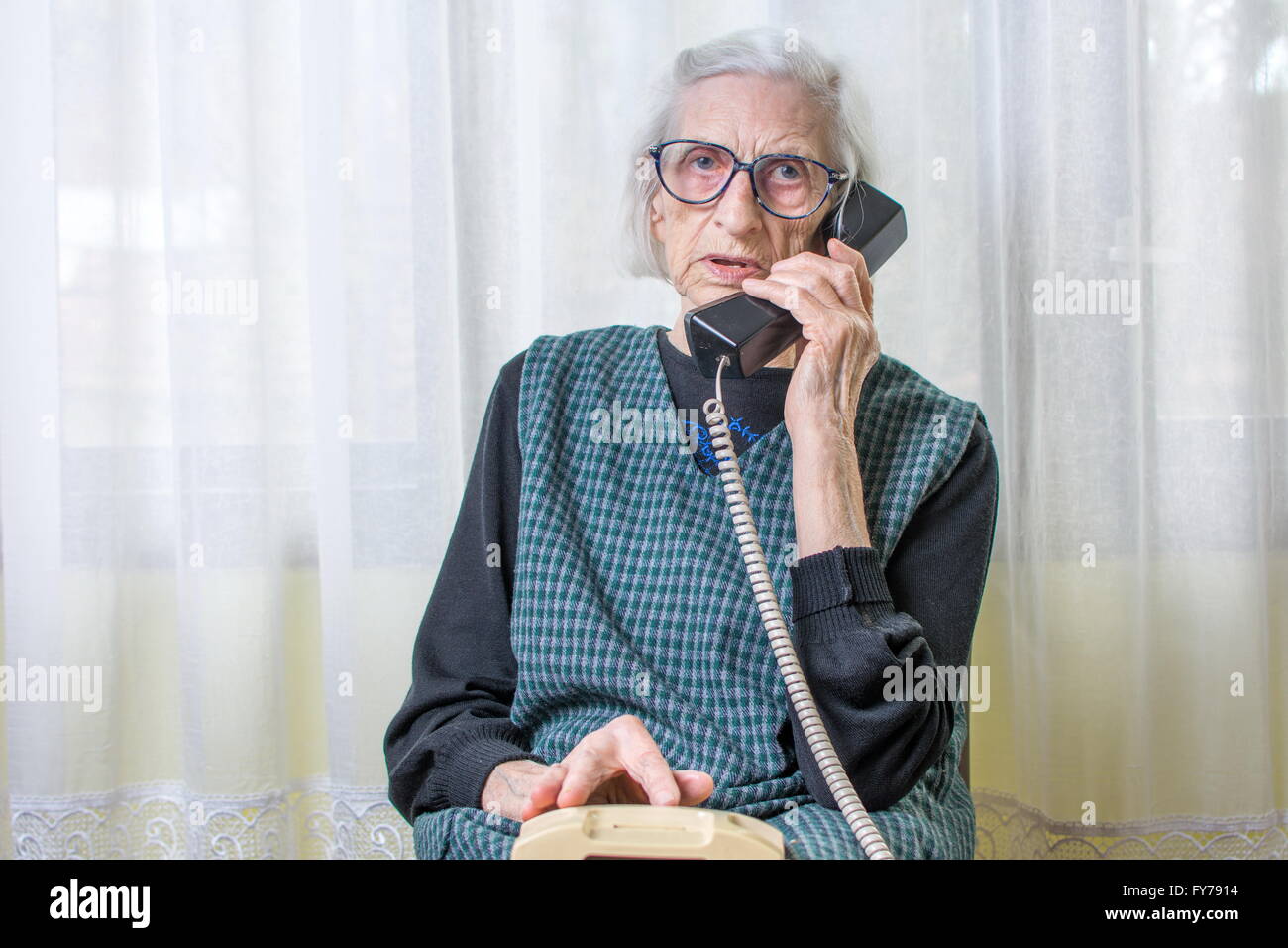 Mujer de 90 años de edad mujer utilizando el teléfono adentro Foto de stock