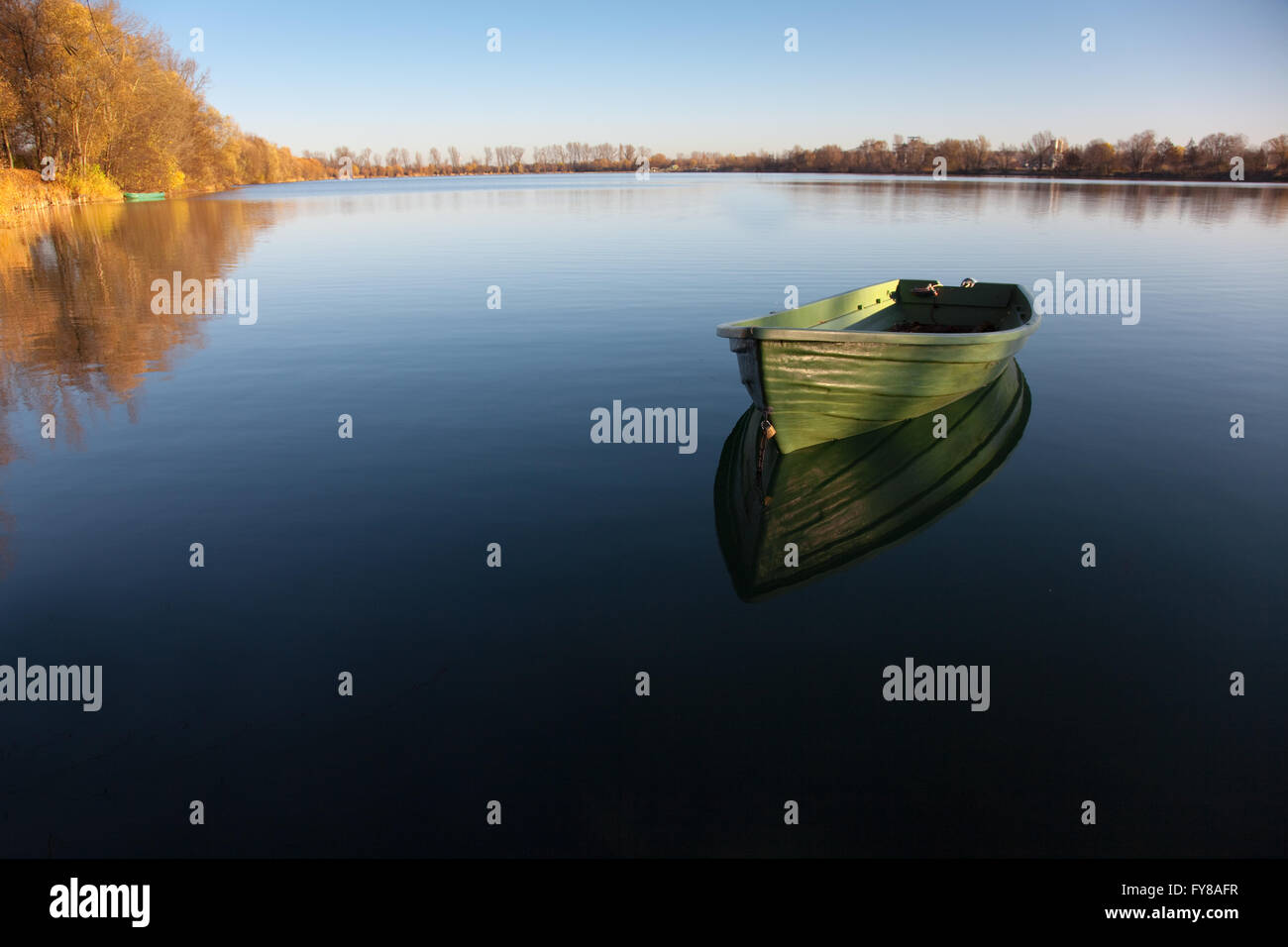 Fila única embarcación en el lago con el reflejo en el agua Foto de stock