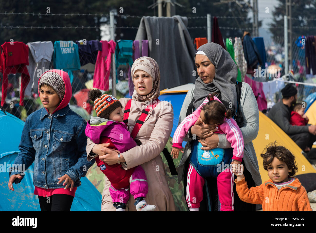 Dos mujeres caminan con sus hijos el 17 de marzo de 2015 en el campamento de refugiados de Eidomeni, Grecia. Foto de stock