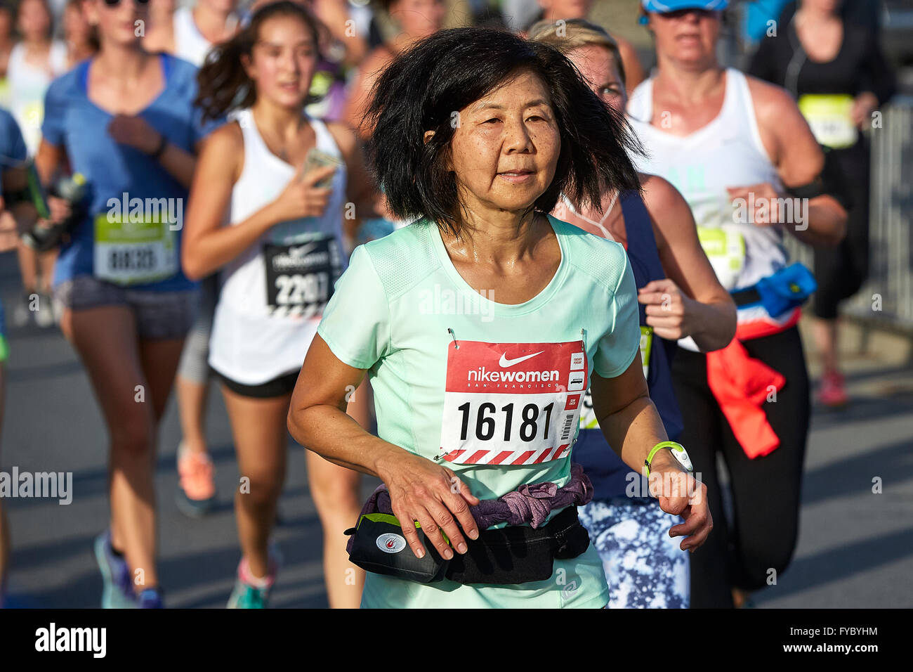 Cometidos de la atleta femenina madura ejecuta en el medio maratón Nike Mujer, San Francisco, 2015. Foto de stock