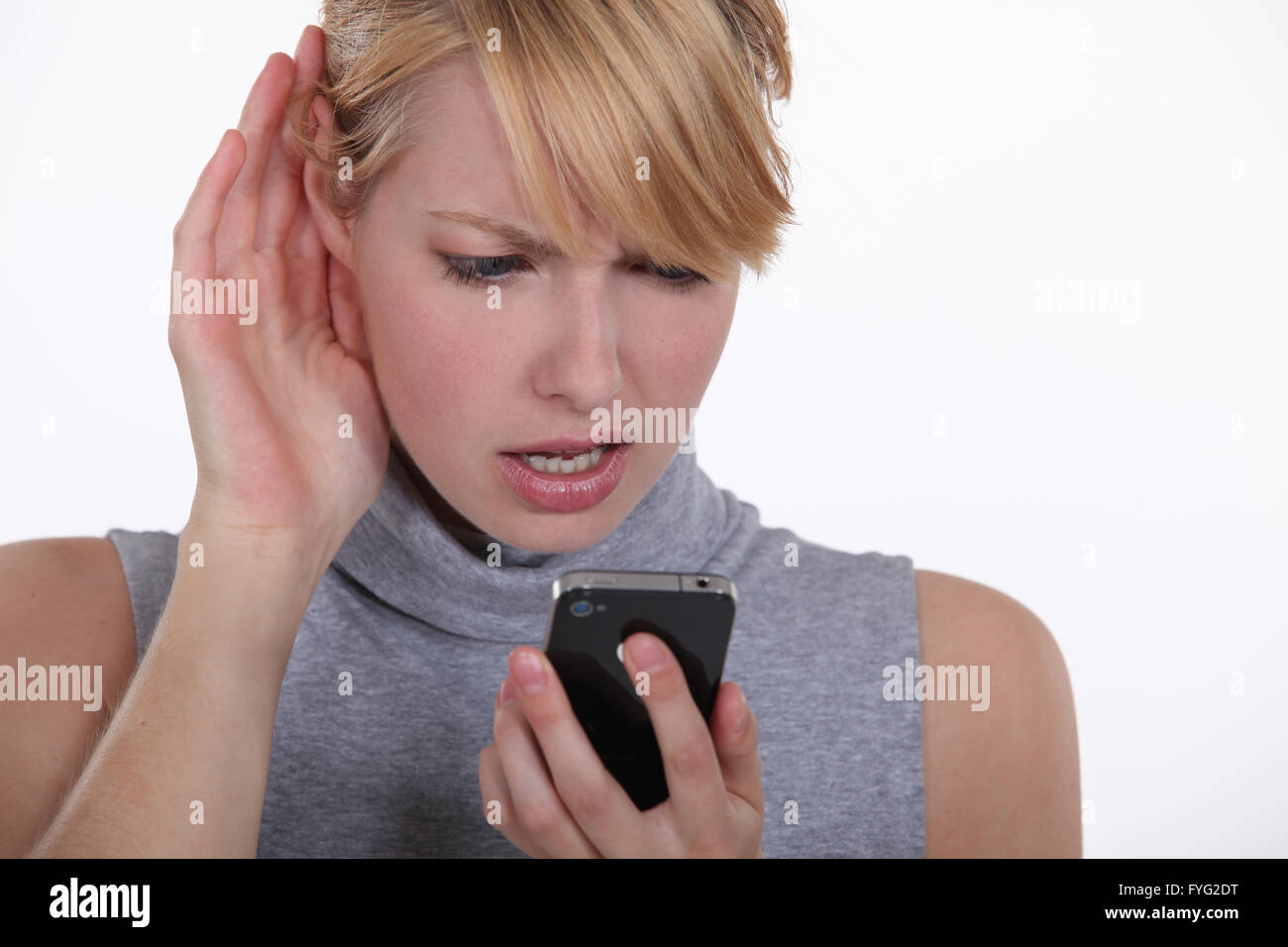 Mujer luchando por tener una conversación de teléfono con altavoz Foto de stock
