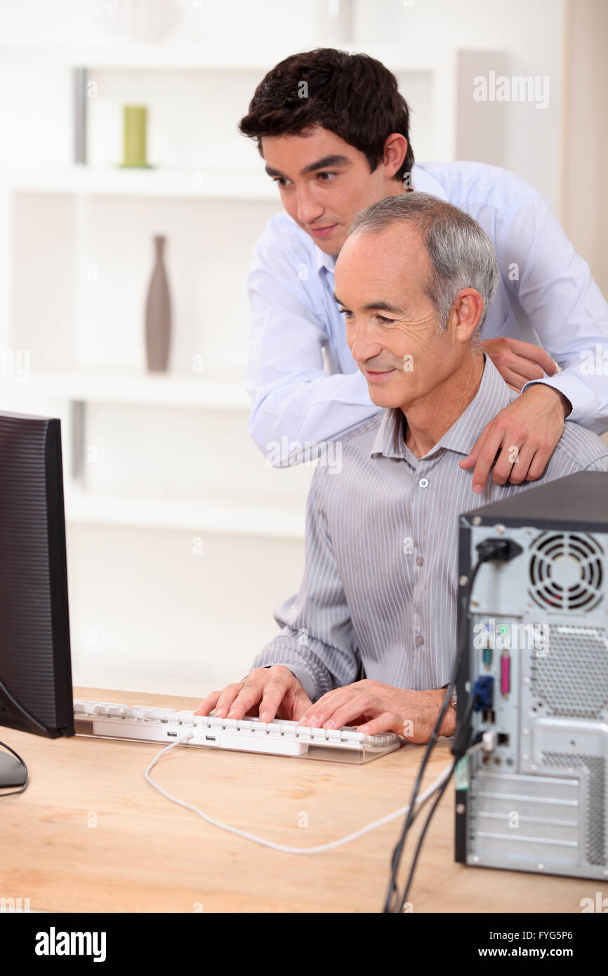 Un padre y su hijo mirando una pantalla de ordenador. Foto de stock