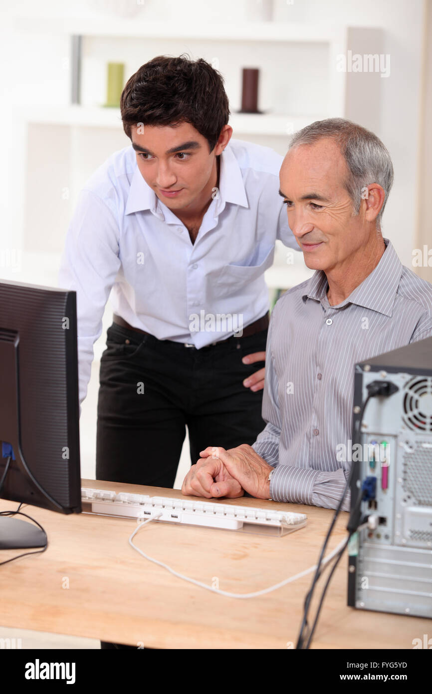 Nieto mostrando su abuelo el uso del ordenador. Foto de stock