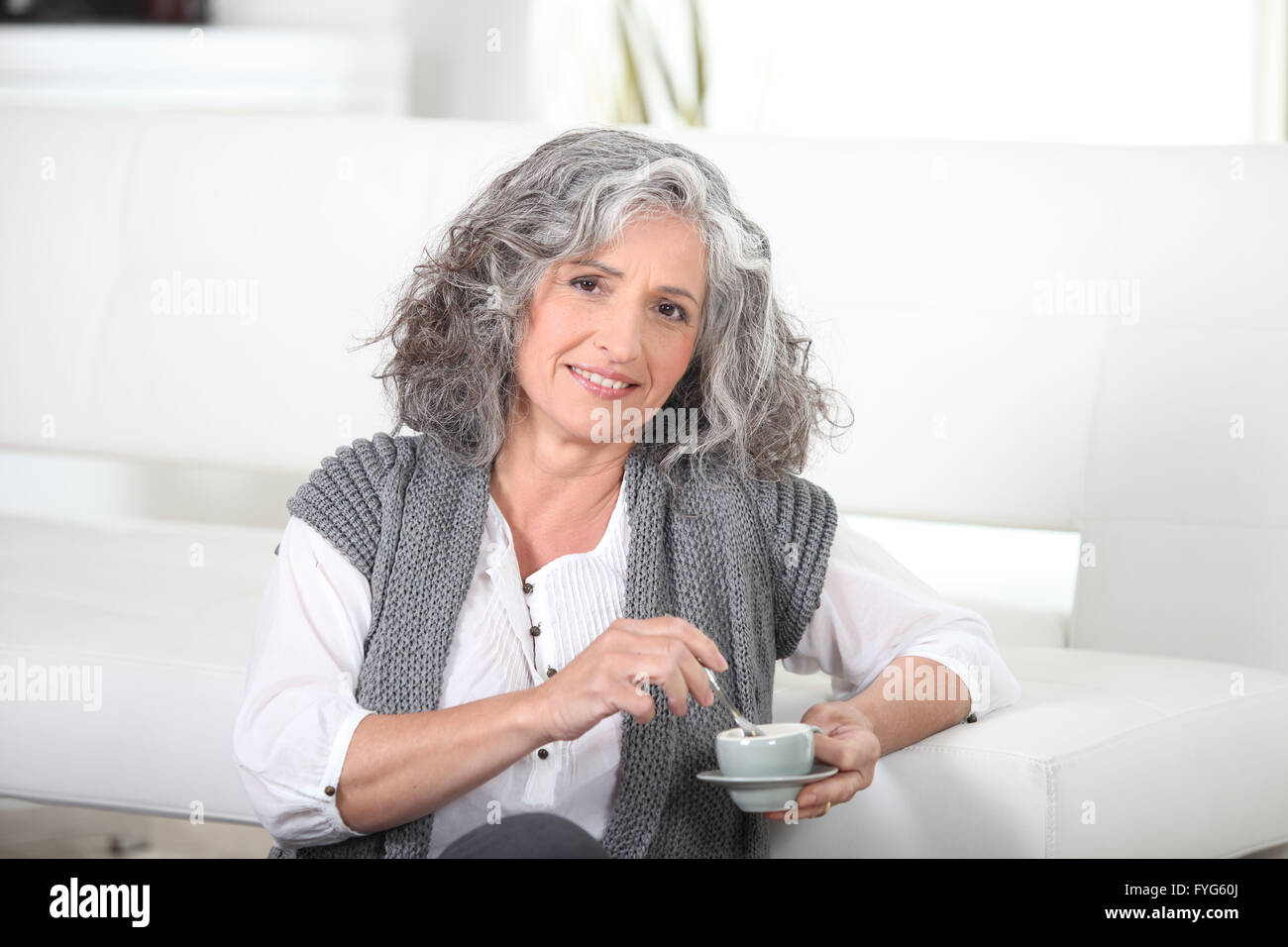 Mujer sentada en el piso con una taza de café Foto de stock
