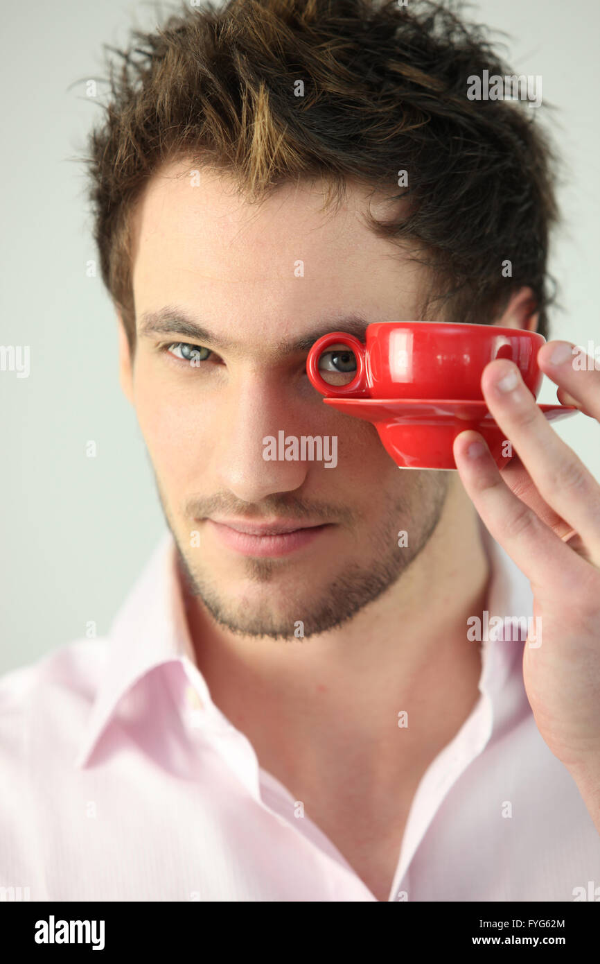 Hombre mirando a través de la manija de una taza de café Foto de stock
