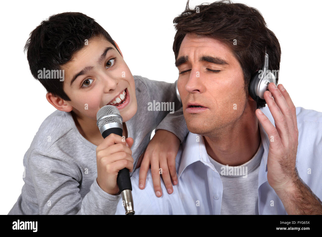 Hombre con auriculares y Little Boy cantando en un micrófono Foto de stock