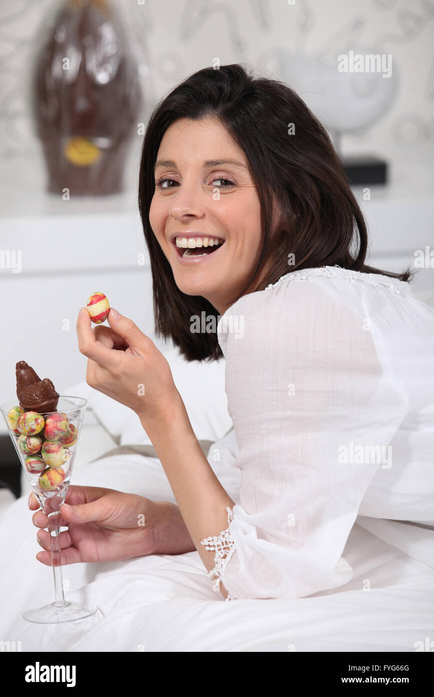 Laughing mujer con un vaso de mini huevos de Pascua Foto de stock