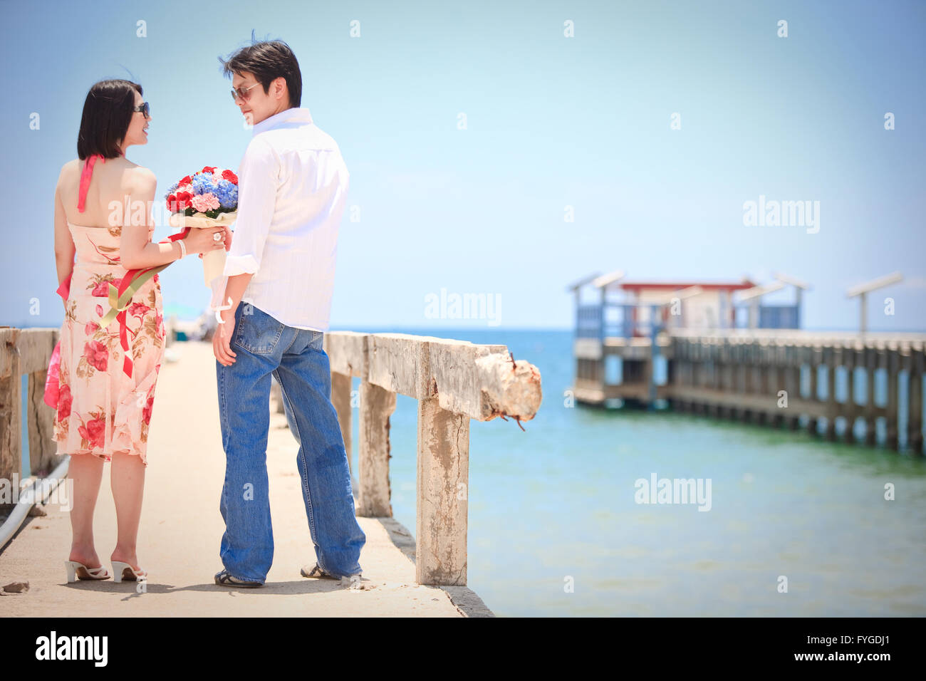 Las parejas toman contacto ocular en el muelle en la playa Foto de stock