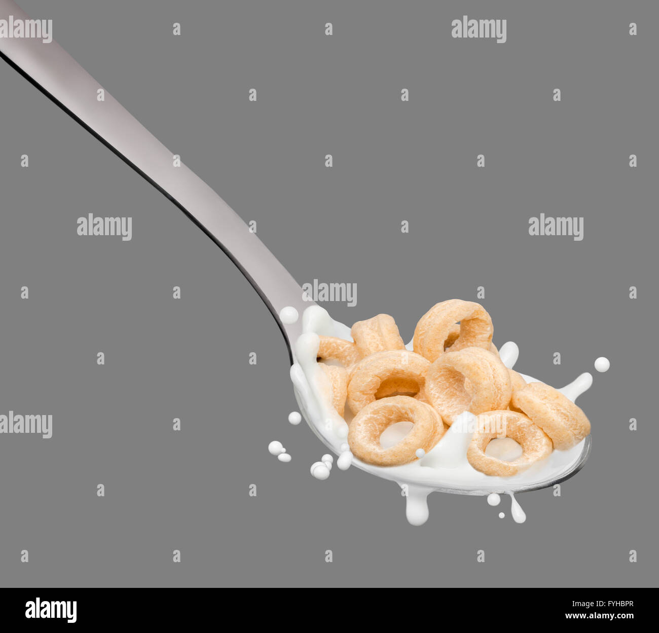Salpicaduras de leche en la cuchara y aros de cereales Foto de stock