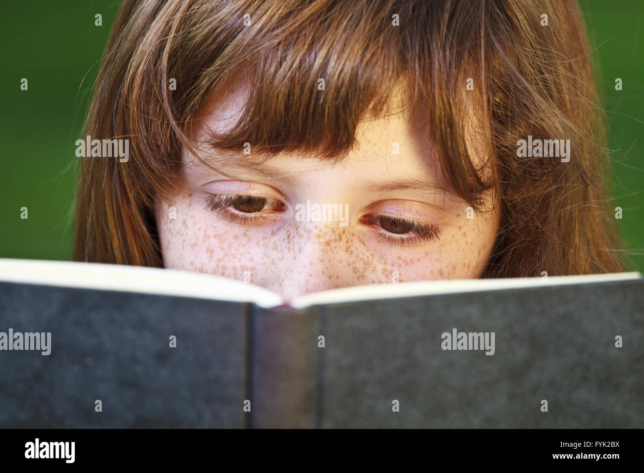 Hermosa joven leyendo un libro en el exterior Foto de stock