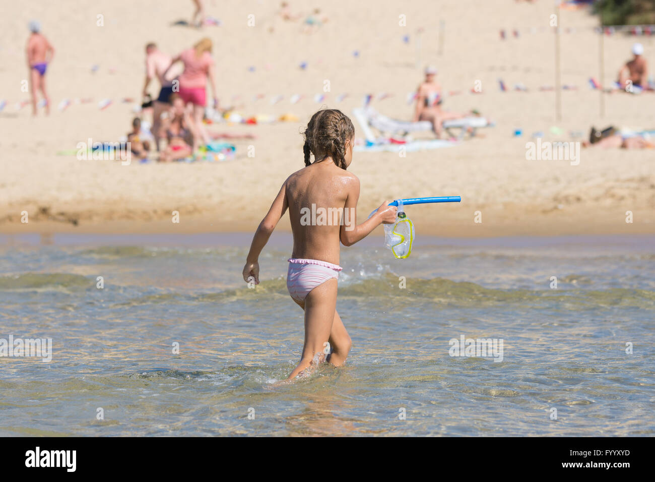 Chica fuera del agua mientras mantiene la máscara y un tubo de natación en sus manos Foto de stock