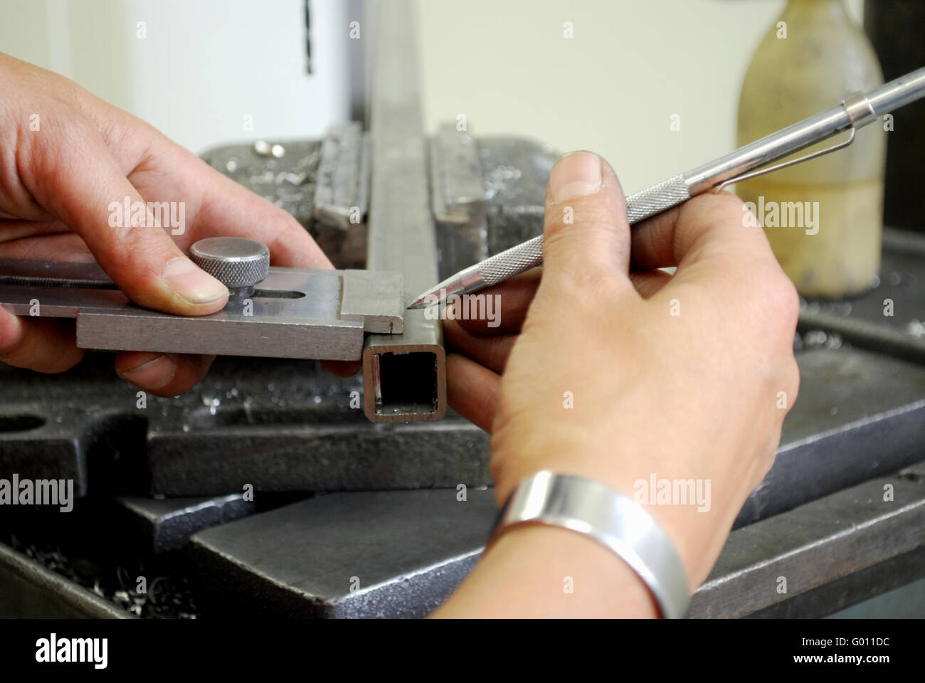 Obrero metalúrgico midiendo un pedazo de metal para taladrar Foto de stock