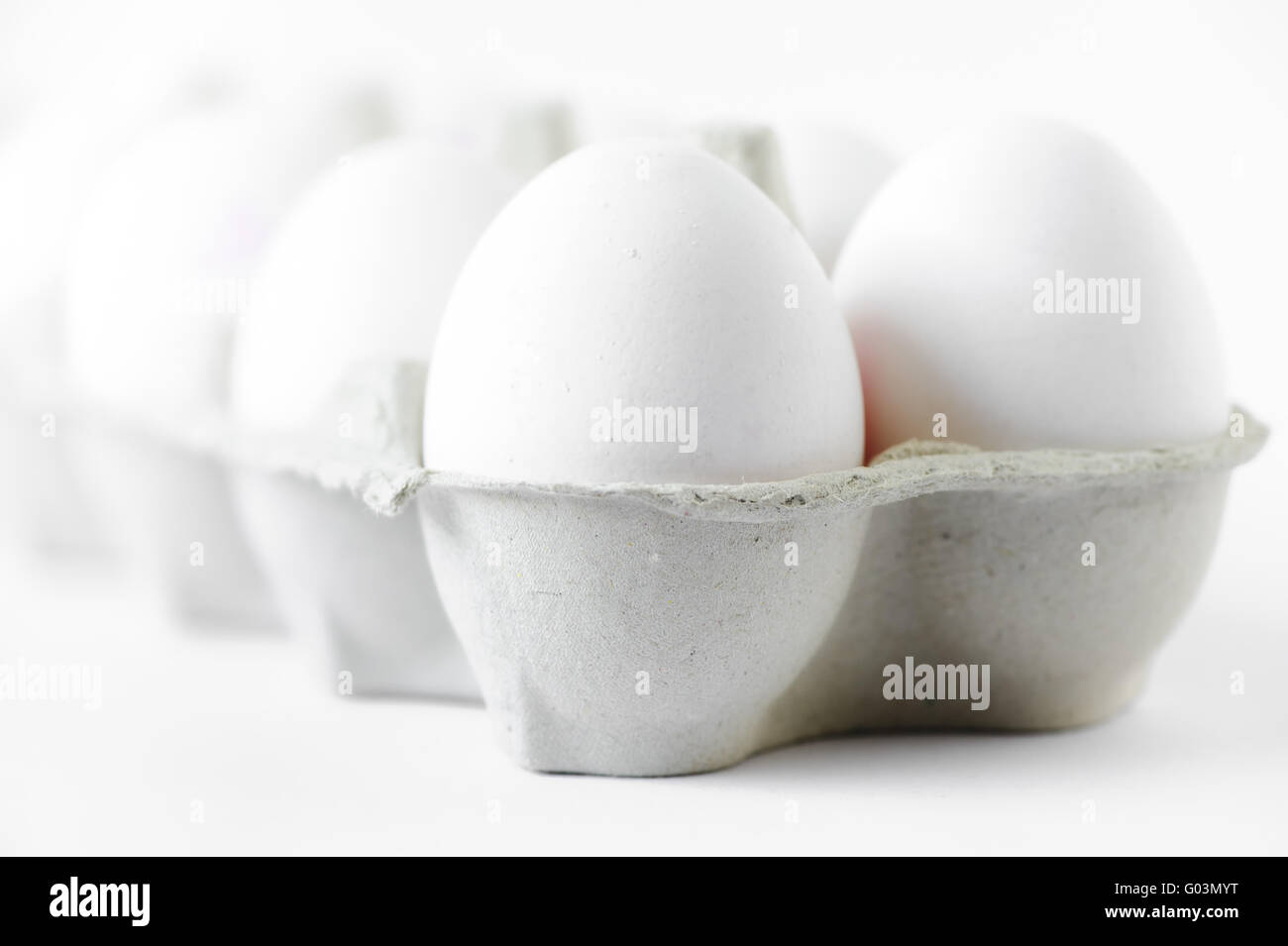10 huevos de gallina en una caja de cartón sobre un fondo blanco Foto de stock