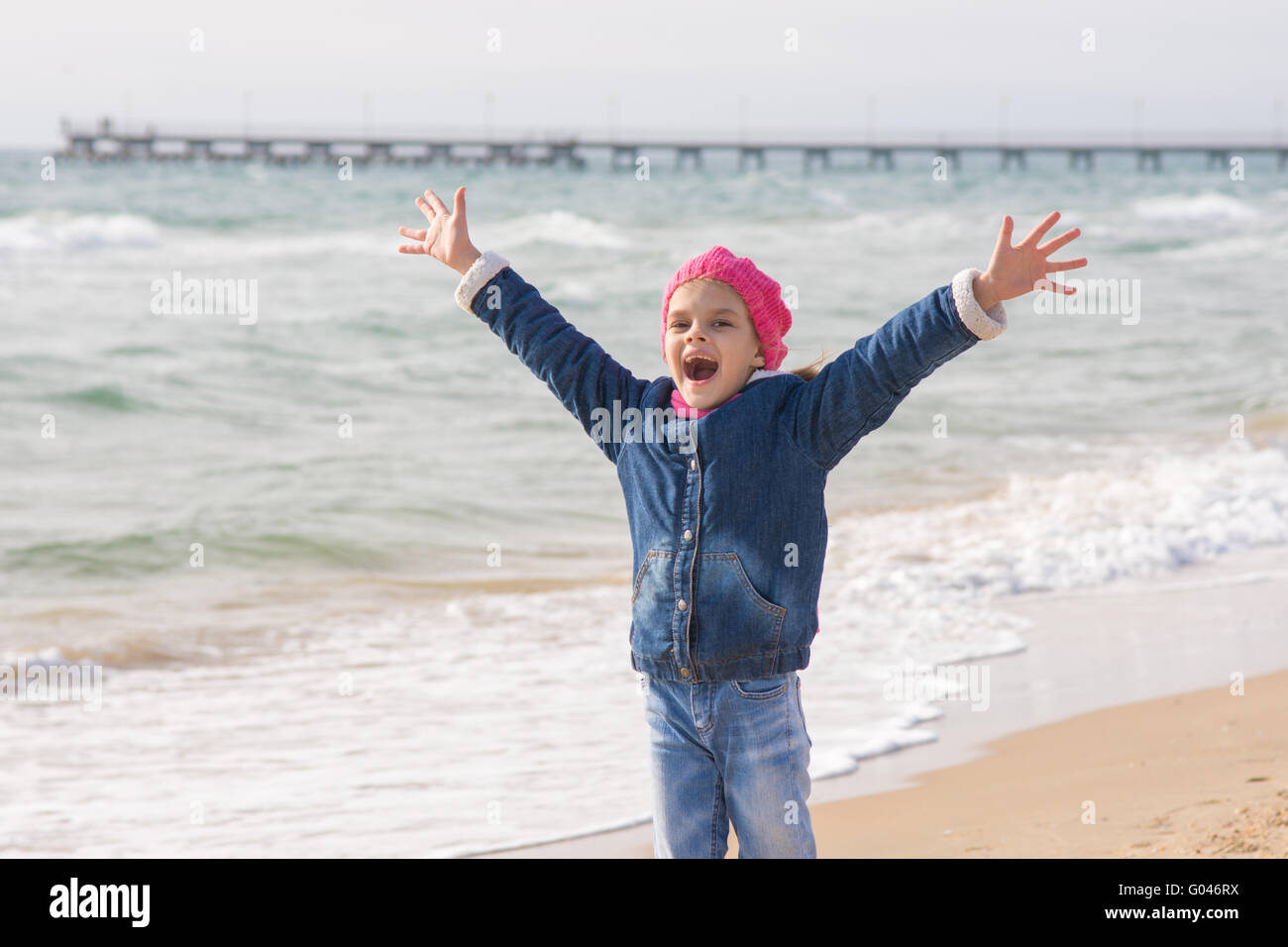 Niña de siete años se alegra la llegada del mar sobre la costa en la primavera Foto de stock