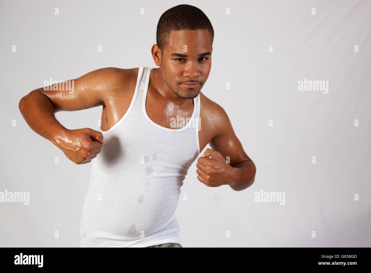 Apuesto joven negro flexionando sus músculos y buscando centrado Foto de stock