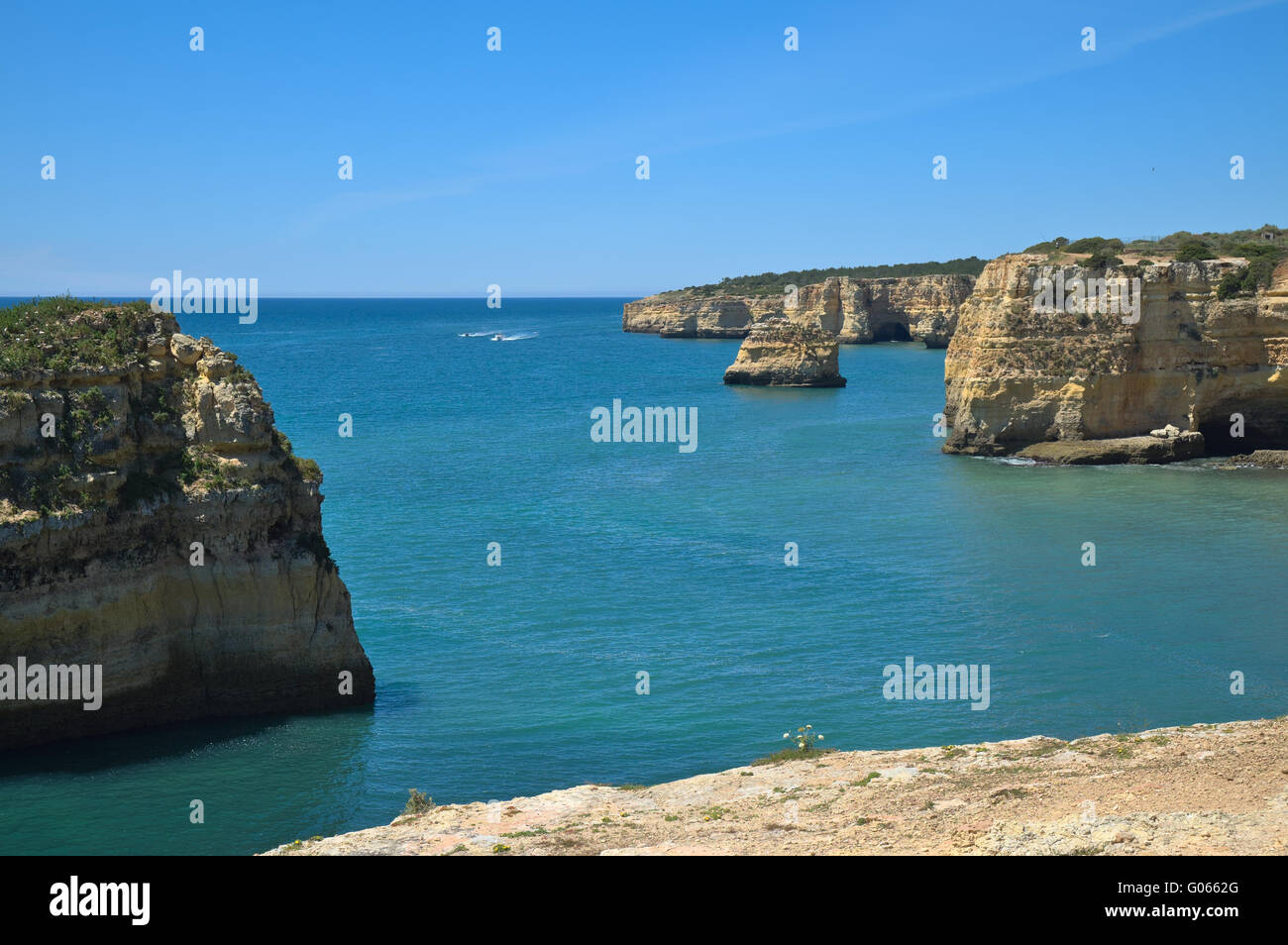 Barco turístico visitando los acantilados y cuevas cerca de la playa de Albandeira, una atracción popular entre los turistas durante la temporada de verano. Foto de stock