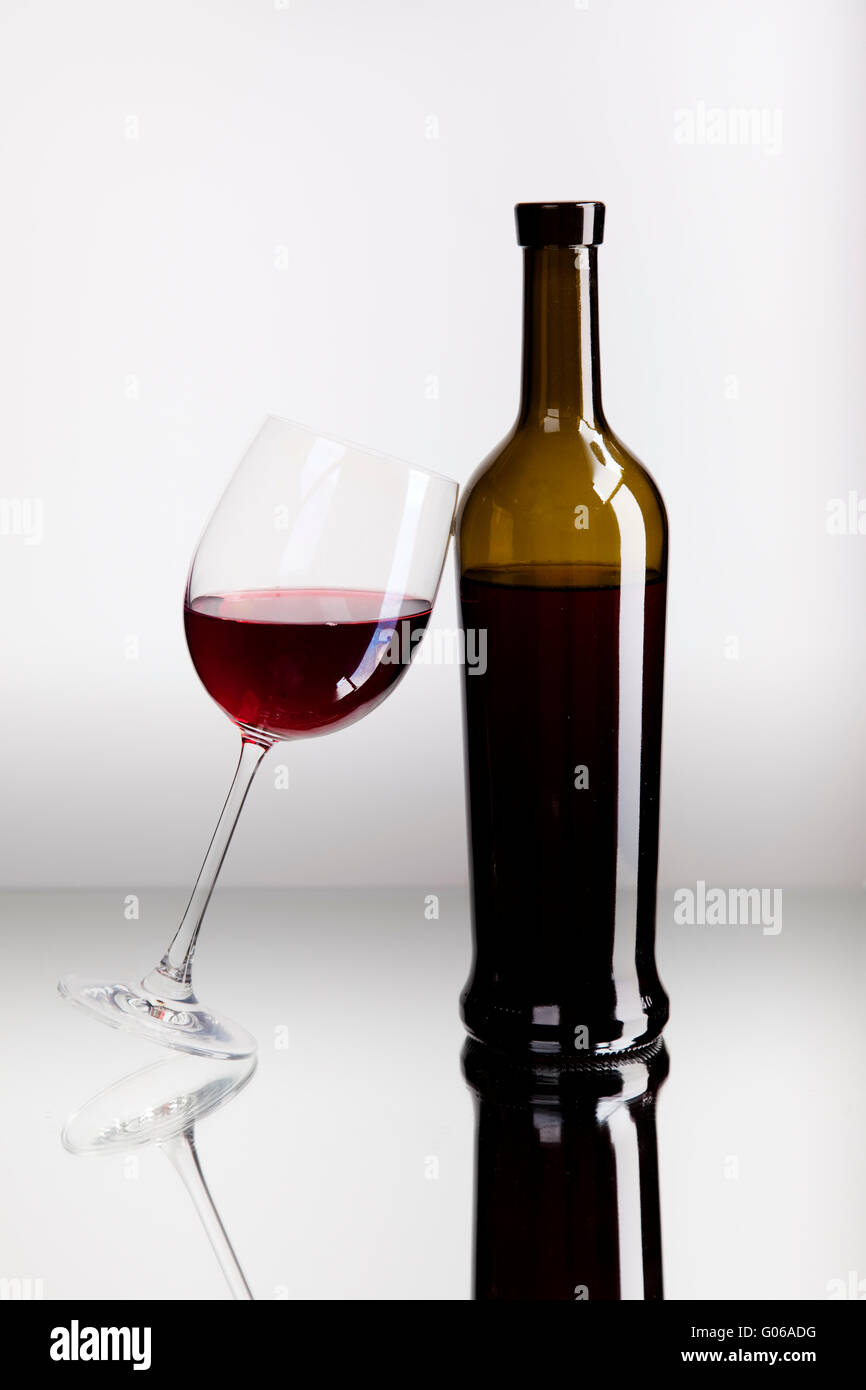 Y una botella de cristal con vino tinto en la superficie del espejo Foto de stock