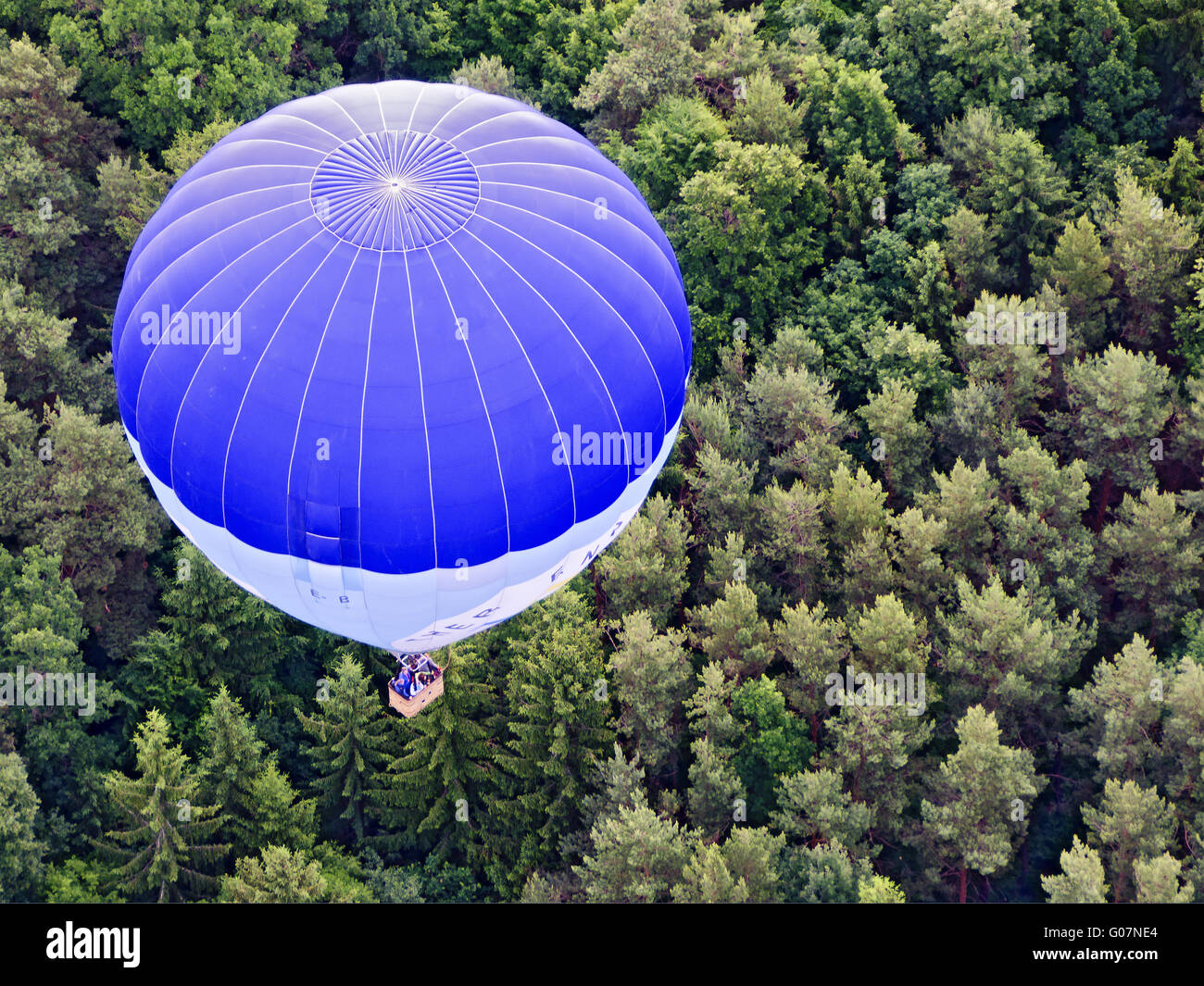 Ot-air balloon flotando sobre un boscoso aera Foto de stock