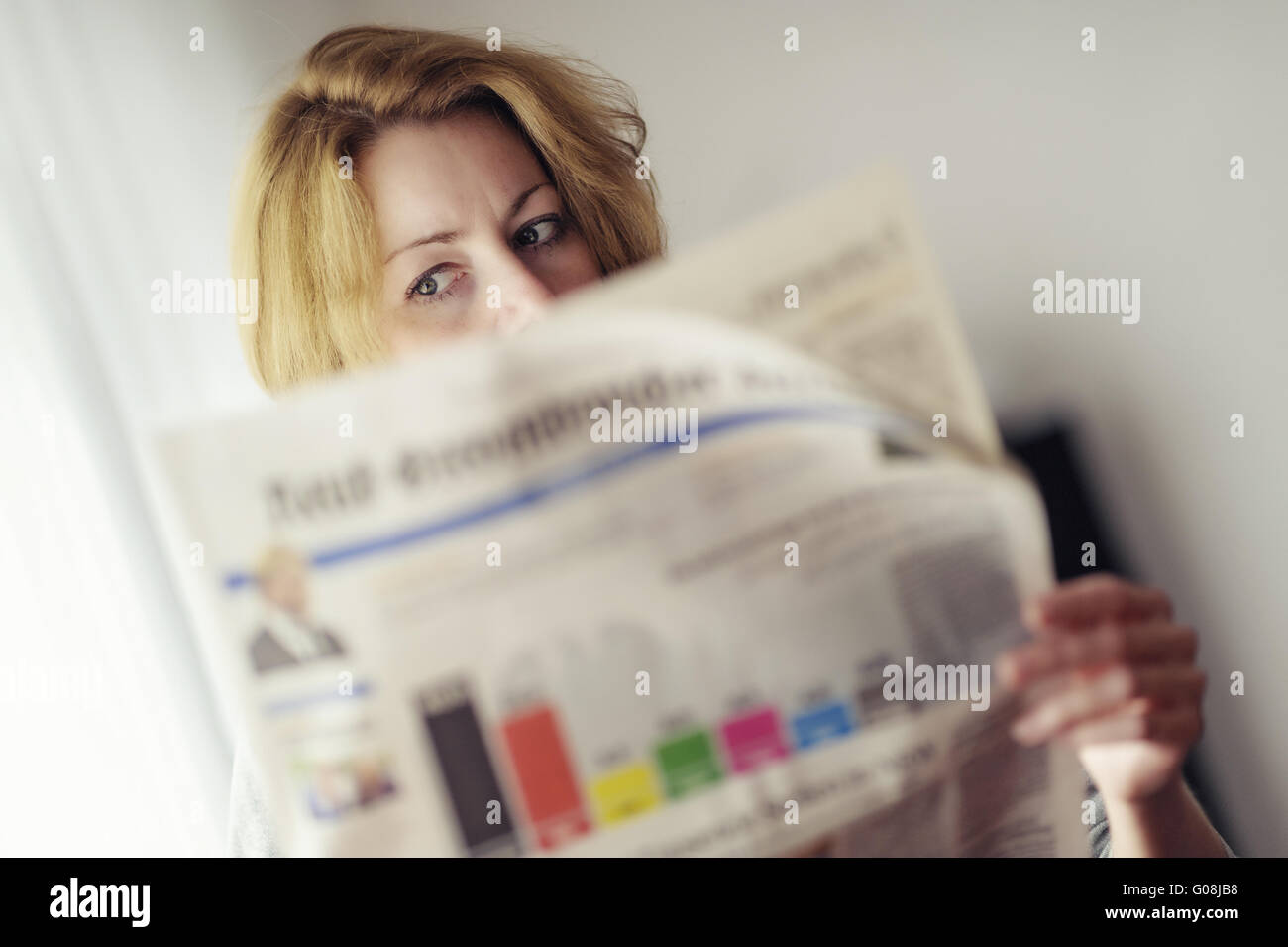 Mujer joven leyendo un periódico con previsiones de Foto de stock