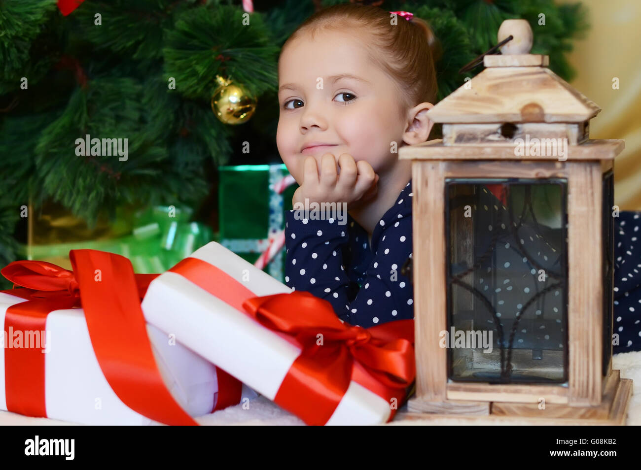 La niña en una Navidad fur-árbol con regalos Foto de stock