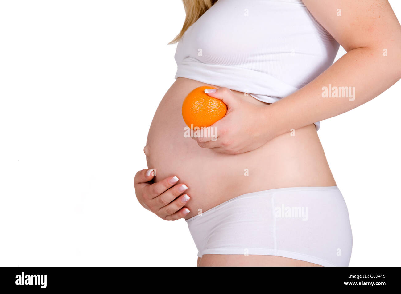 Presentación de naranja en frente de mi embarazada vientre Foto de stock