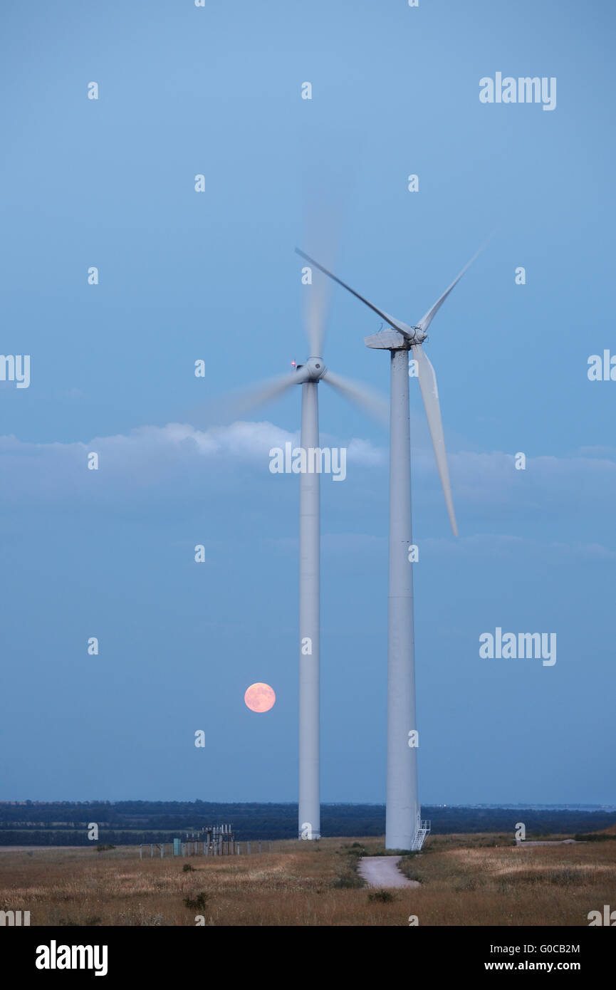Las turbinas de la central eólica y la luna llena en el cielo Foto de stock
