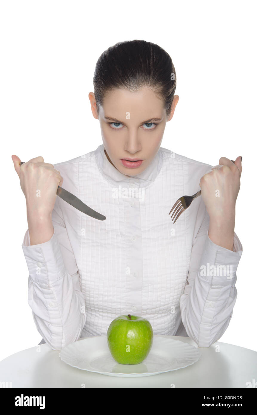 Mujer joven come una manzana con un tenedor y un cuchillo Foto de stock