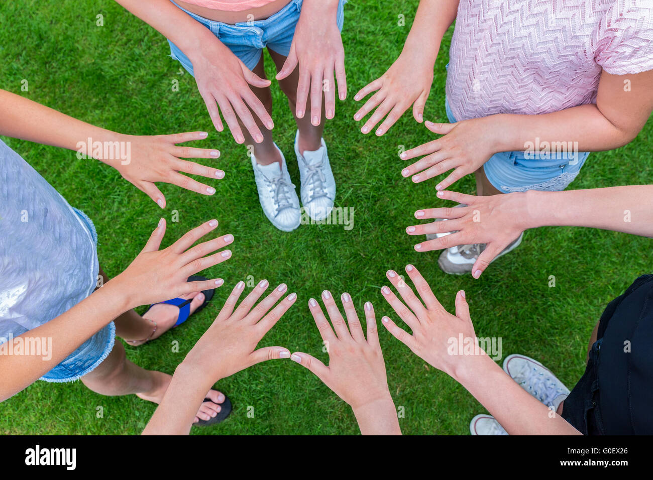 Muchos niños manos uniéndose en círculo por encima de hierba Foto de stock
