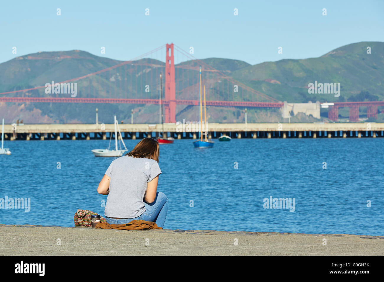 Mujer joven sentada dibujando en el parque acuático de la costa de San Francisco. Foto de stock