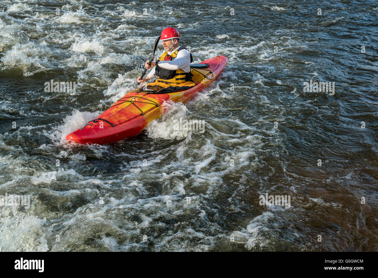 Whitewater senior kayakista remando río arriba por el río rápido Foto de stock