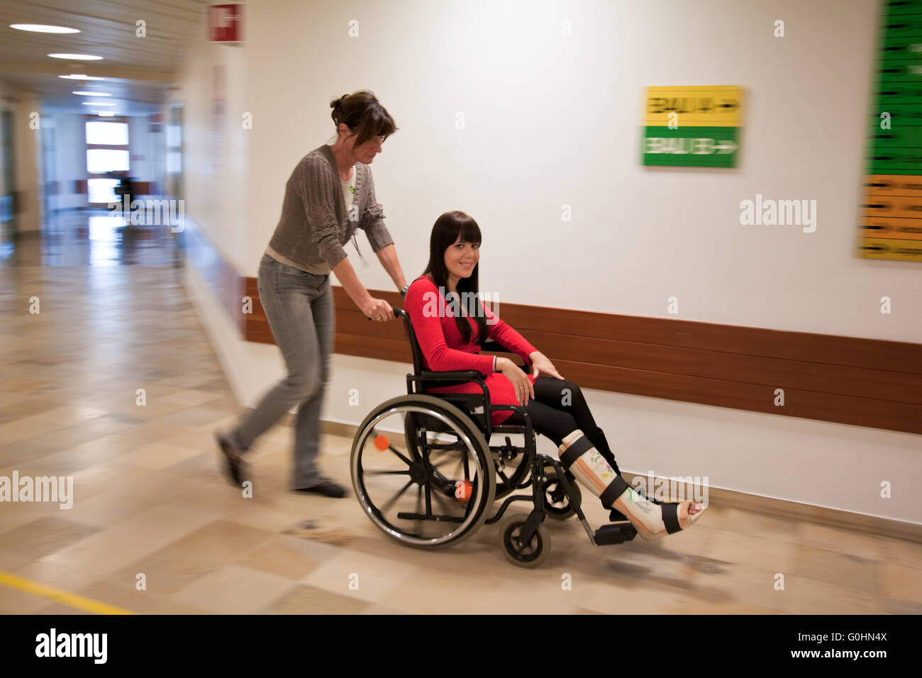 Mujer con yeso en la pierna, y una enfermera Rollstruhl Foto de stock
